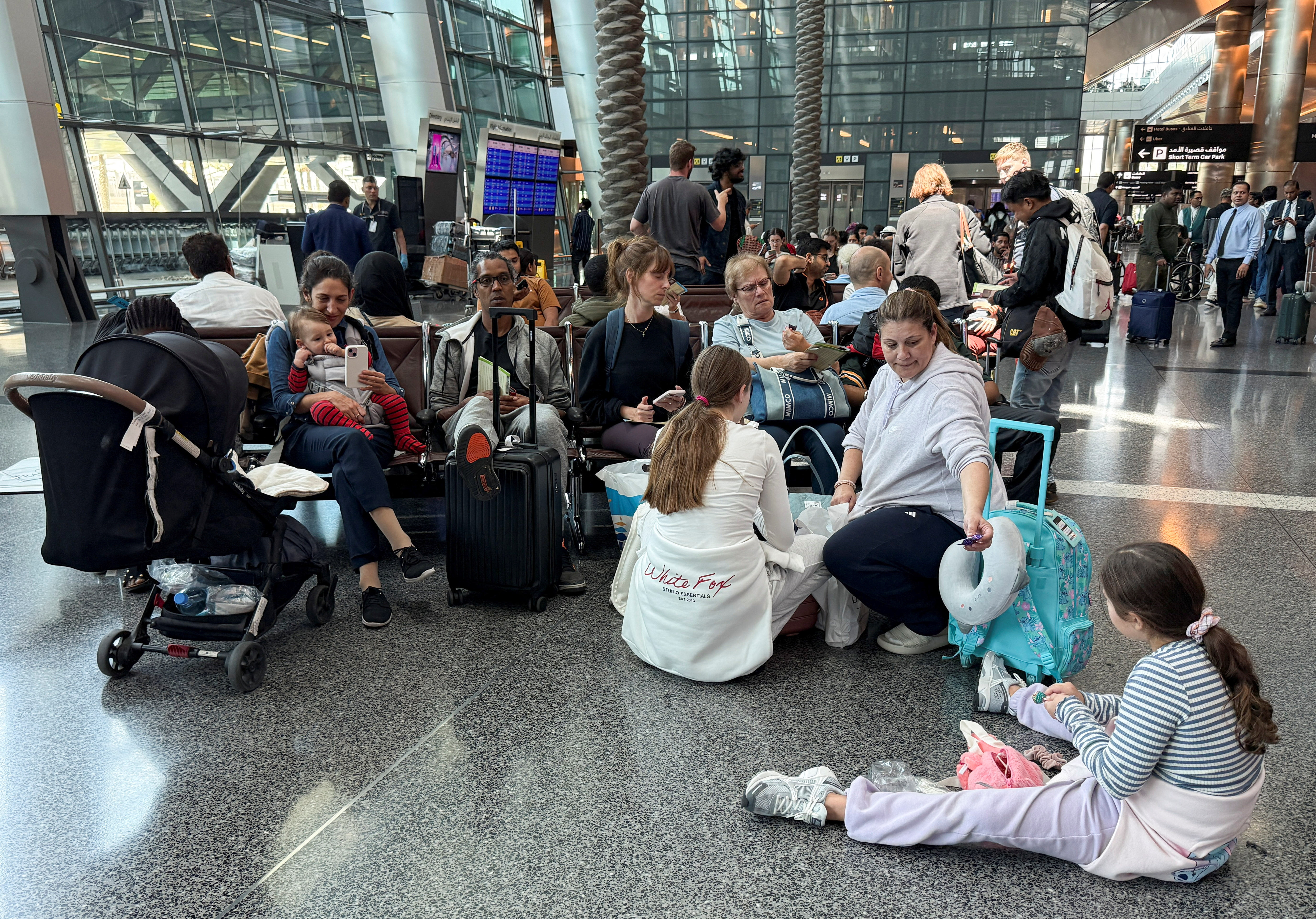 People sit at Hamad International Airport after Qatar reopened its airspace following a brief closure in the wake of Iran’s missile attack on Al Udeid Air Base on Monday, in Doha, Qatar, June 24, 2025.