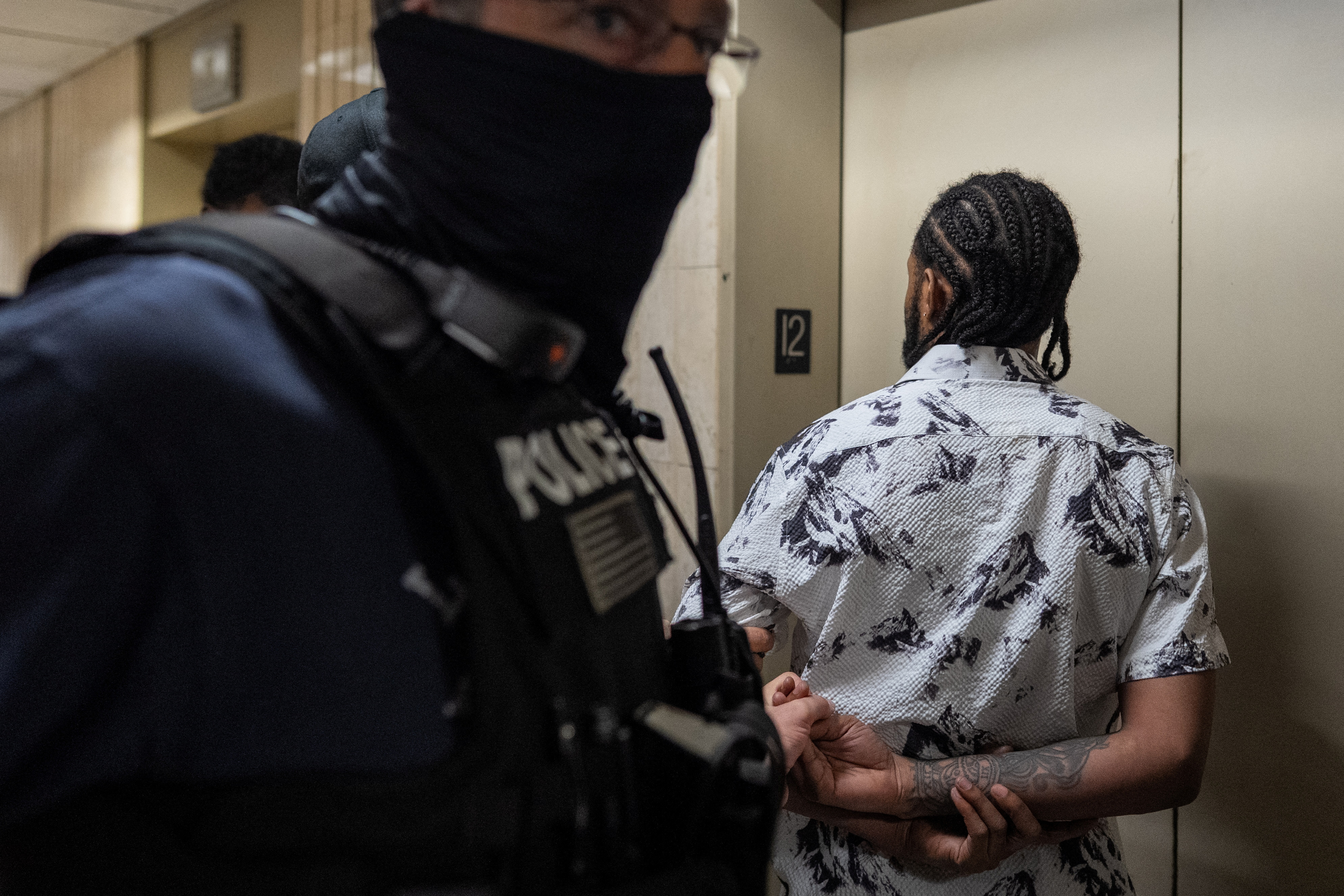 Immigration agents make an arrest by pressing a man against a wall and handcuffing him behind his back.