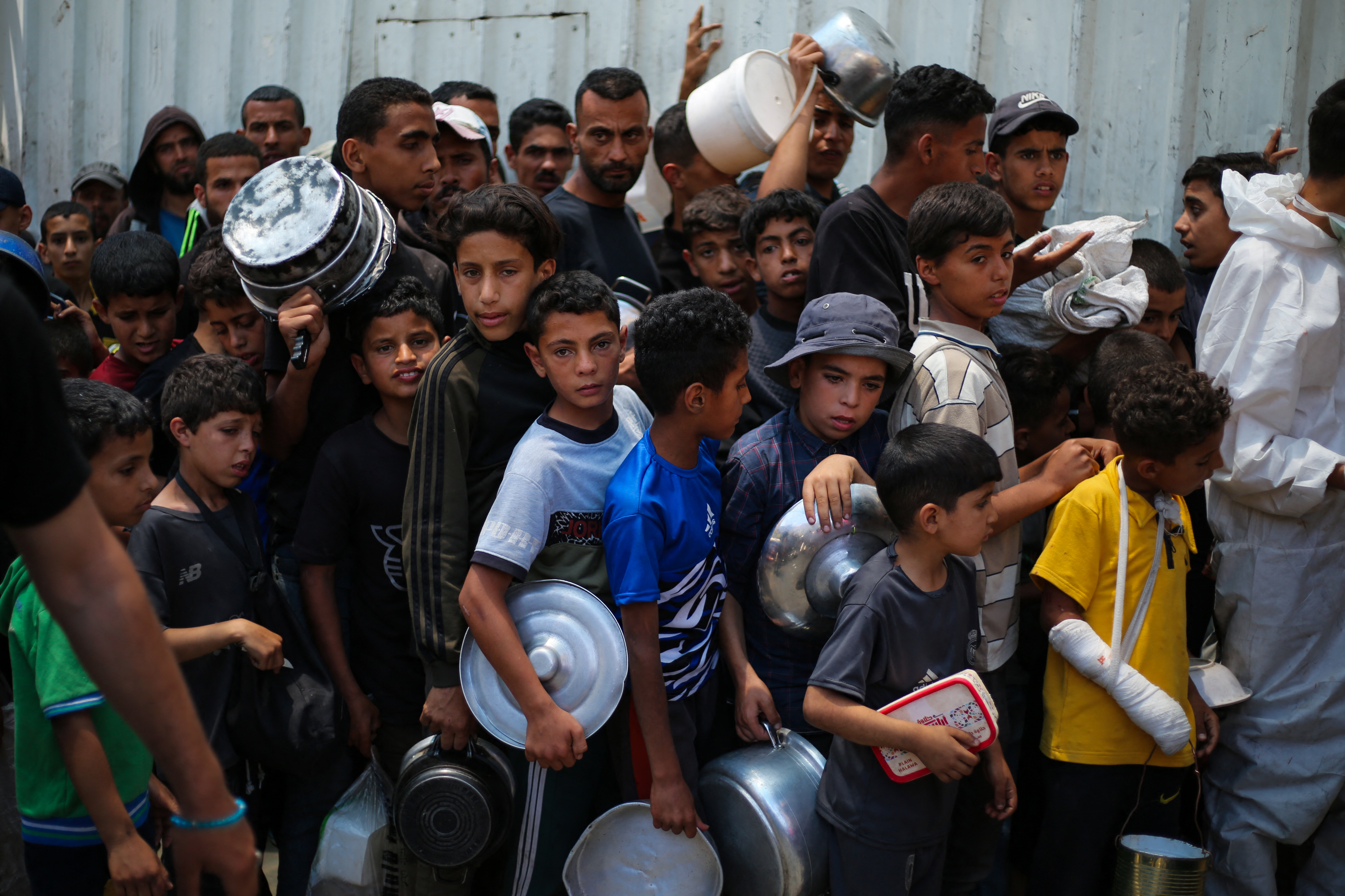 Palestinian children wait with others for food at a distribution point in Nuseirat, central Gaza