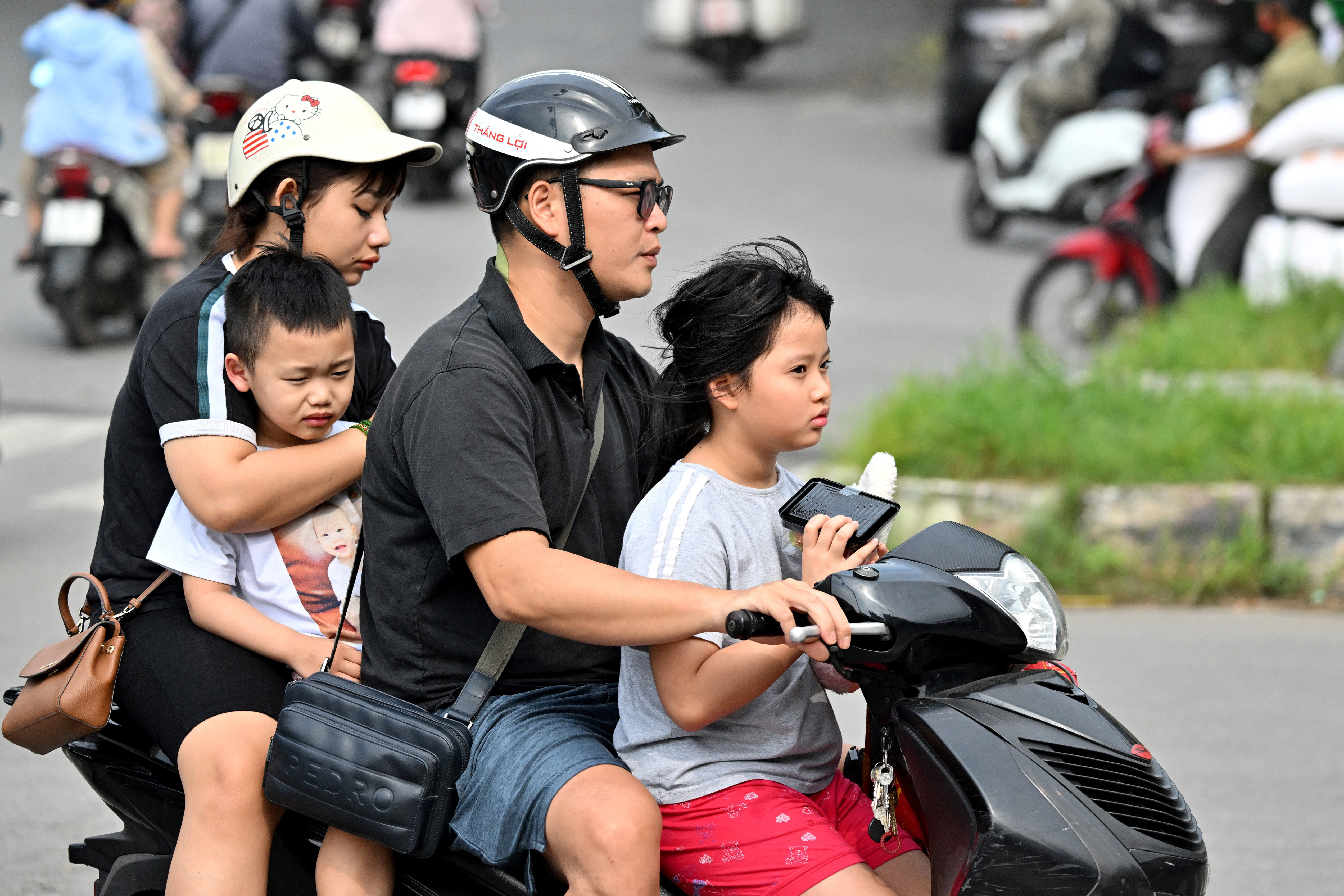 A family rides a motorcycle along a street in Hanoi on June 4, 2025. Vietnam has scrapped a long-standing policy of limiting families to two children, state media said on June 4, as the communist-run country contends with a declining birth rate. (Photo by Nhac NGUYEN / AFP)