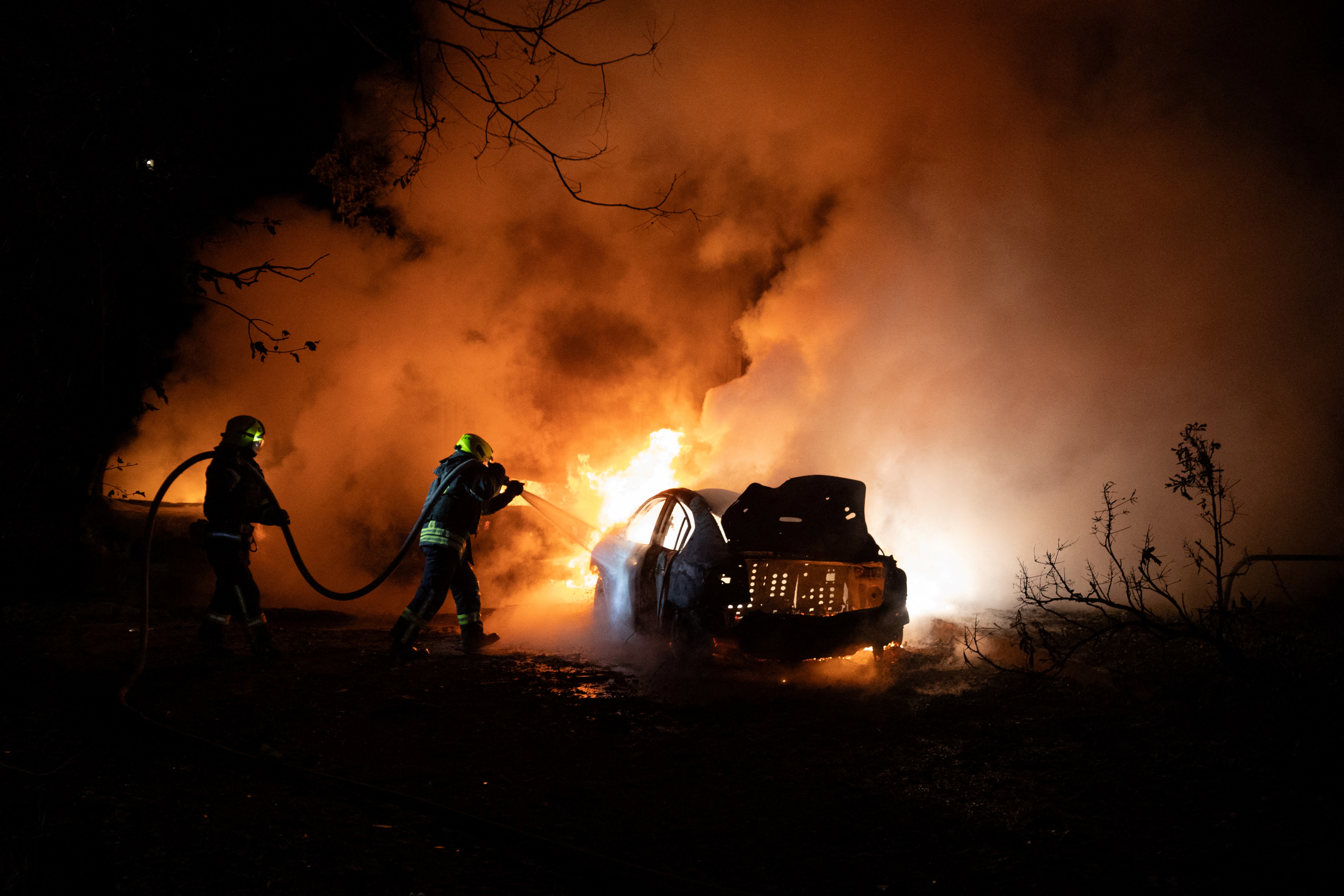 Firefighters extinguish a fire on a damaged car following a drone strike in Kharkiv