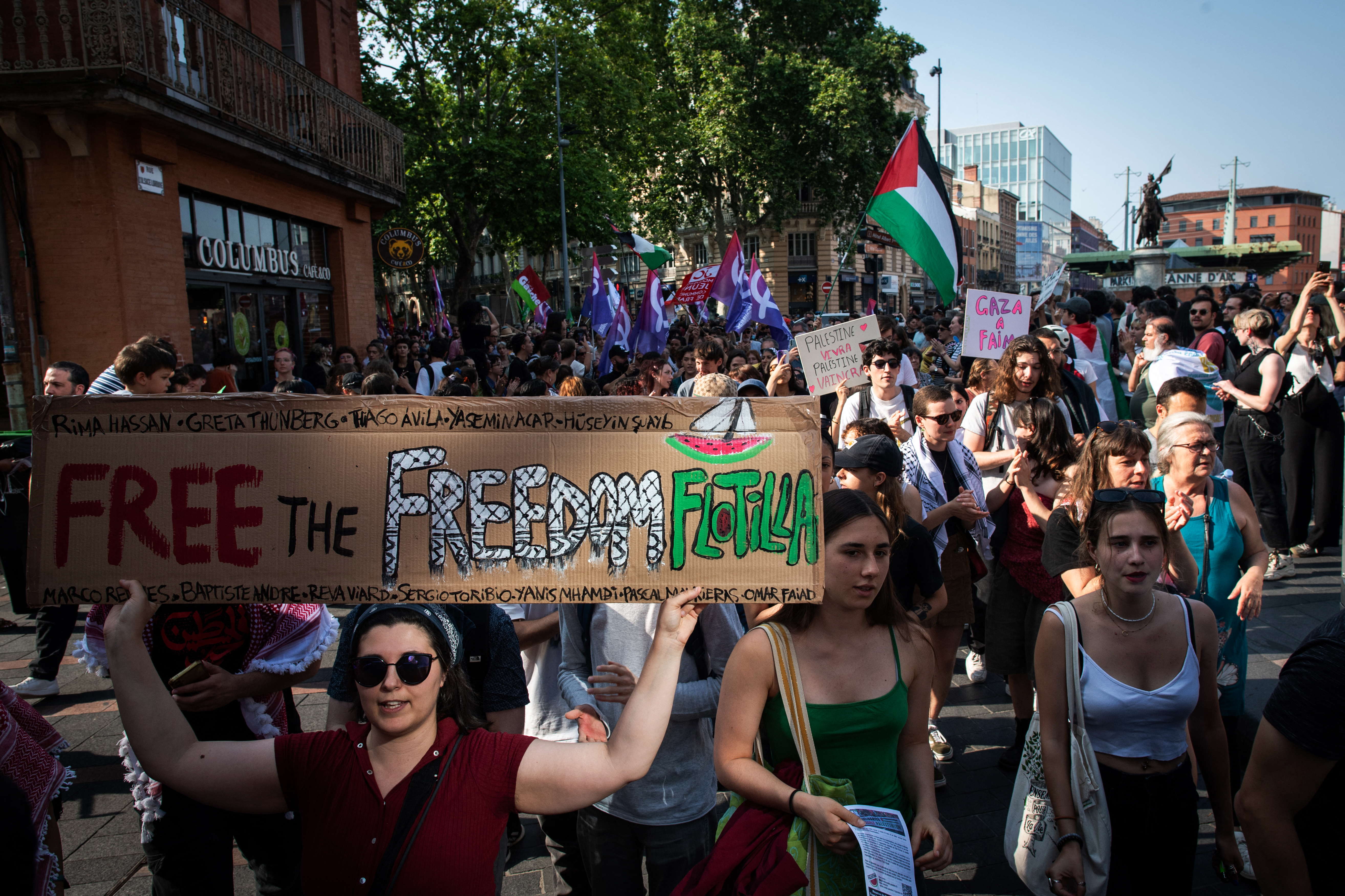 people hold Palestinian flags at a protest