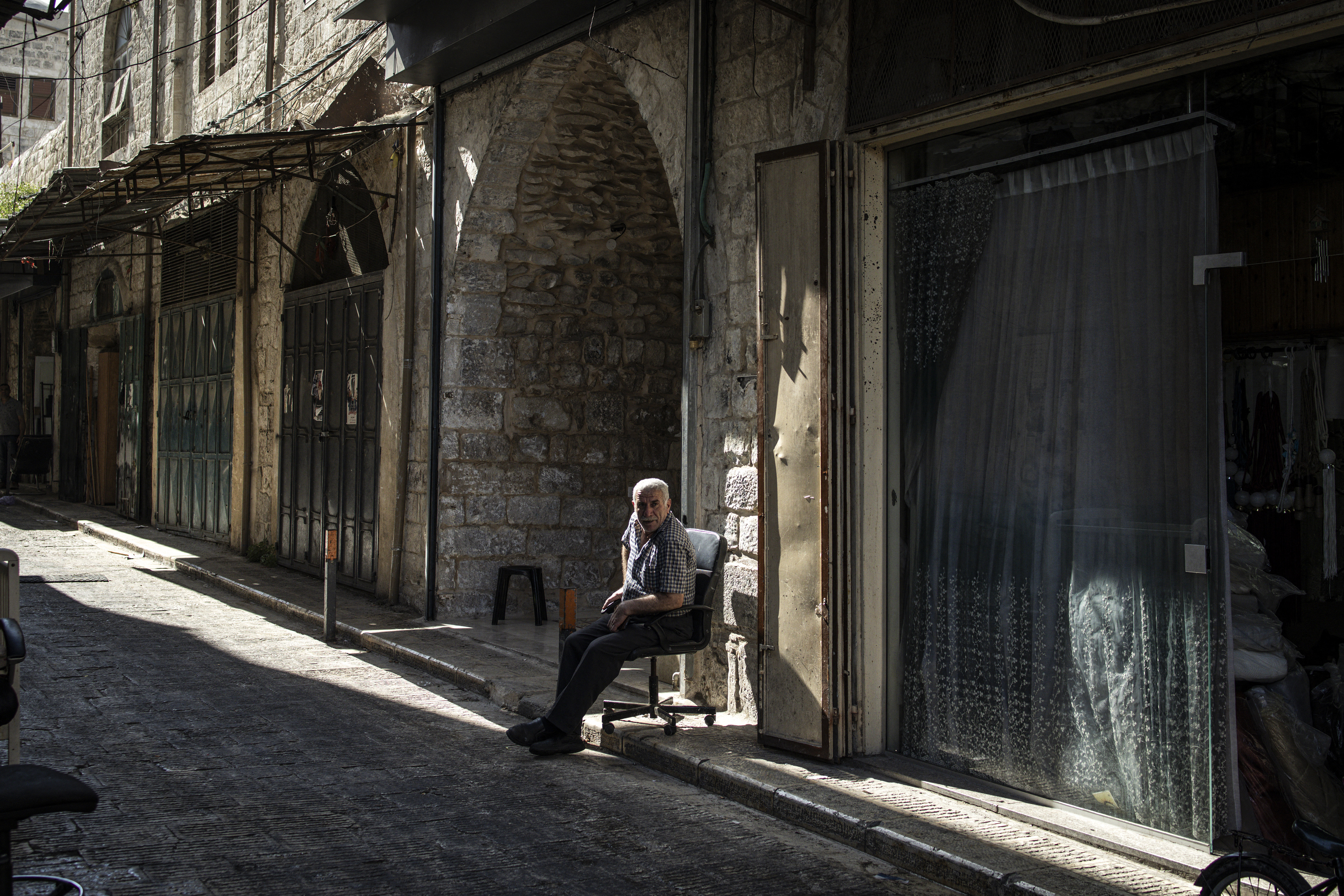 A Palestinian man sits in the sun in an alley, a day after a large-scale Israeli military raid in the old town of Nablus city in the occupied West Bank on June 11, 2025. Israel has occupied the West Bank since 1967, and violence there has soared since the start of the Gaza war in 2023. The West Bank is home to about three million Palestinians, but also some 500,000 Israelis living in settlements that are illegal under international law. (Photo by JOHN WESSELS / AFP)