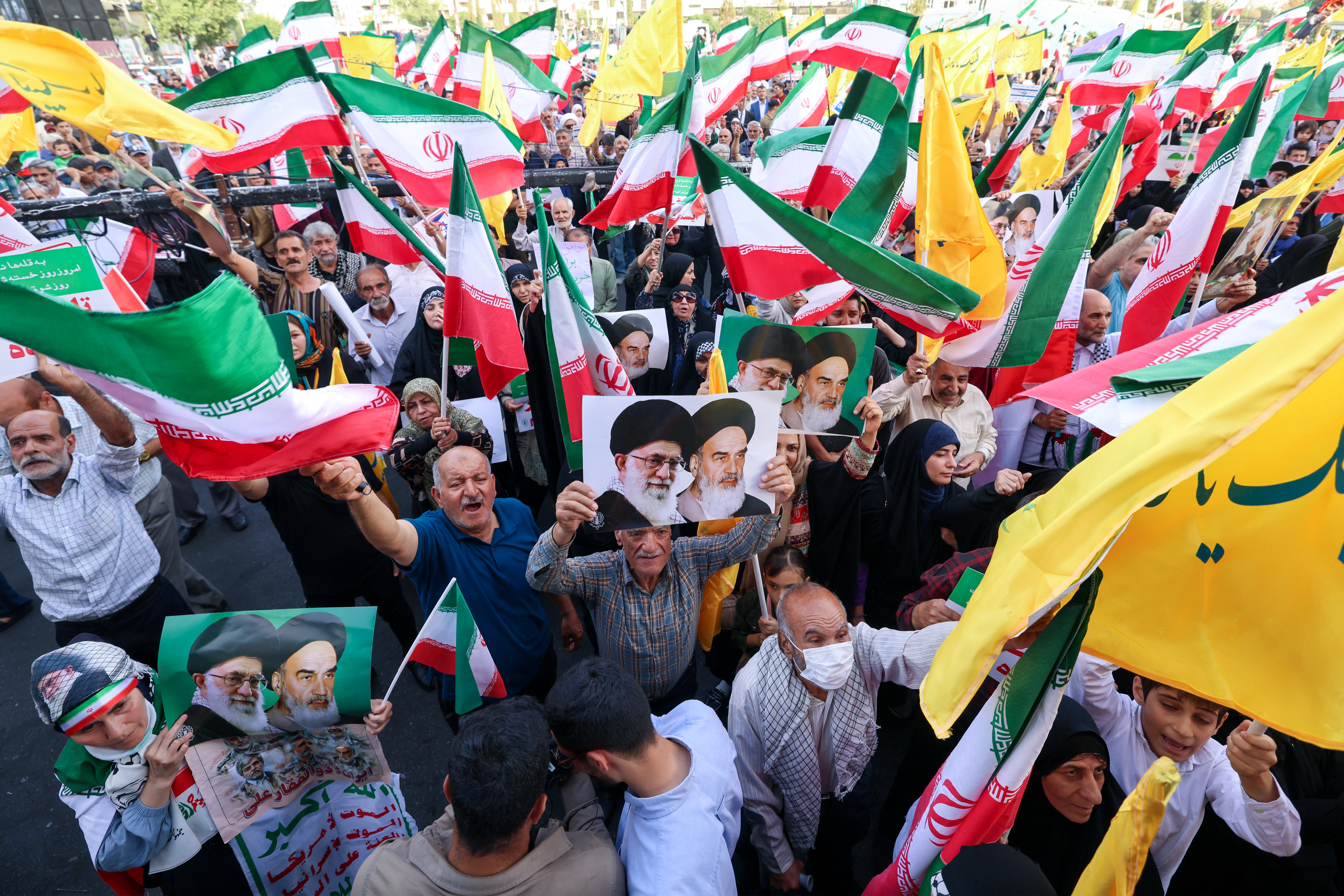 Iranians chant slogans, wave national flags, and hold portraits of Iranian supreme leader Ayatollah Ali Khamenei (L) and late supreme leader Ayatollah Ruhollah Khomeini, as they celebrate a ceasefire between Iran and Israel at Enghlab Square in the capital Tehran on June 24, 2025. A fragile ceasefire in the Iran-Israel war appeared to be holding on June 24, after 12 days of strikes that saw Israel and the United States pummel the Islamic republic's nuclear facilities. (Photo by ATTA KENARE / AFP