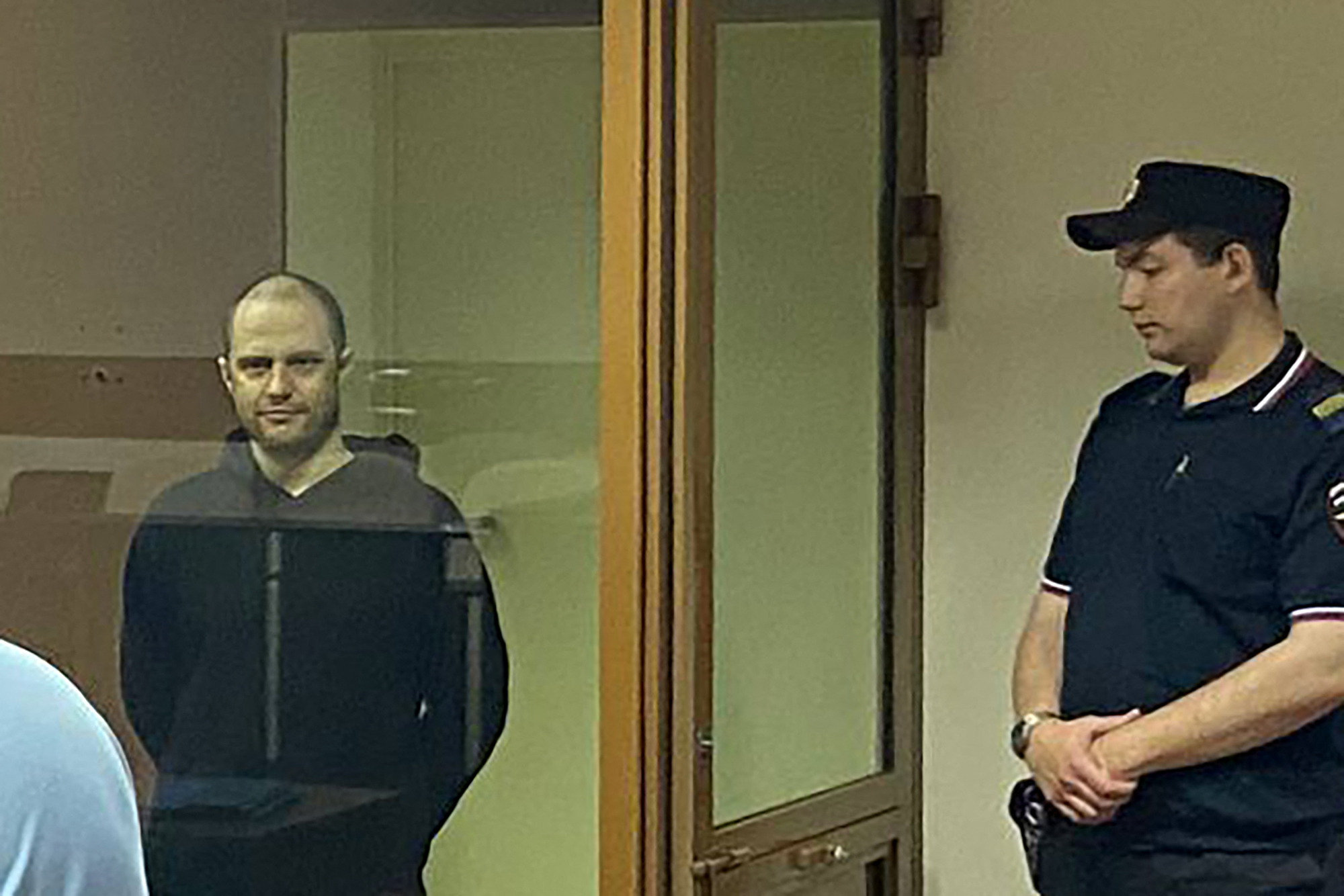 Photographer Grigory Skvortsov stands inside the glass defendants' box during the verdict announcement.