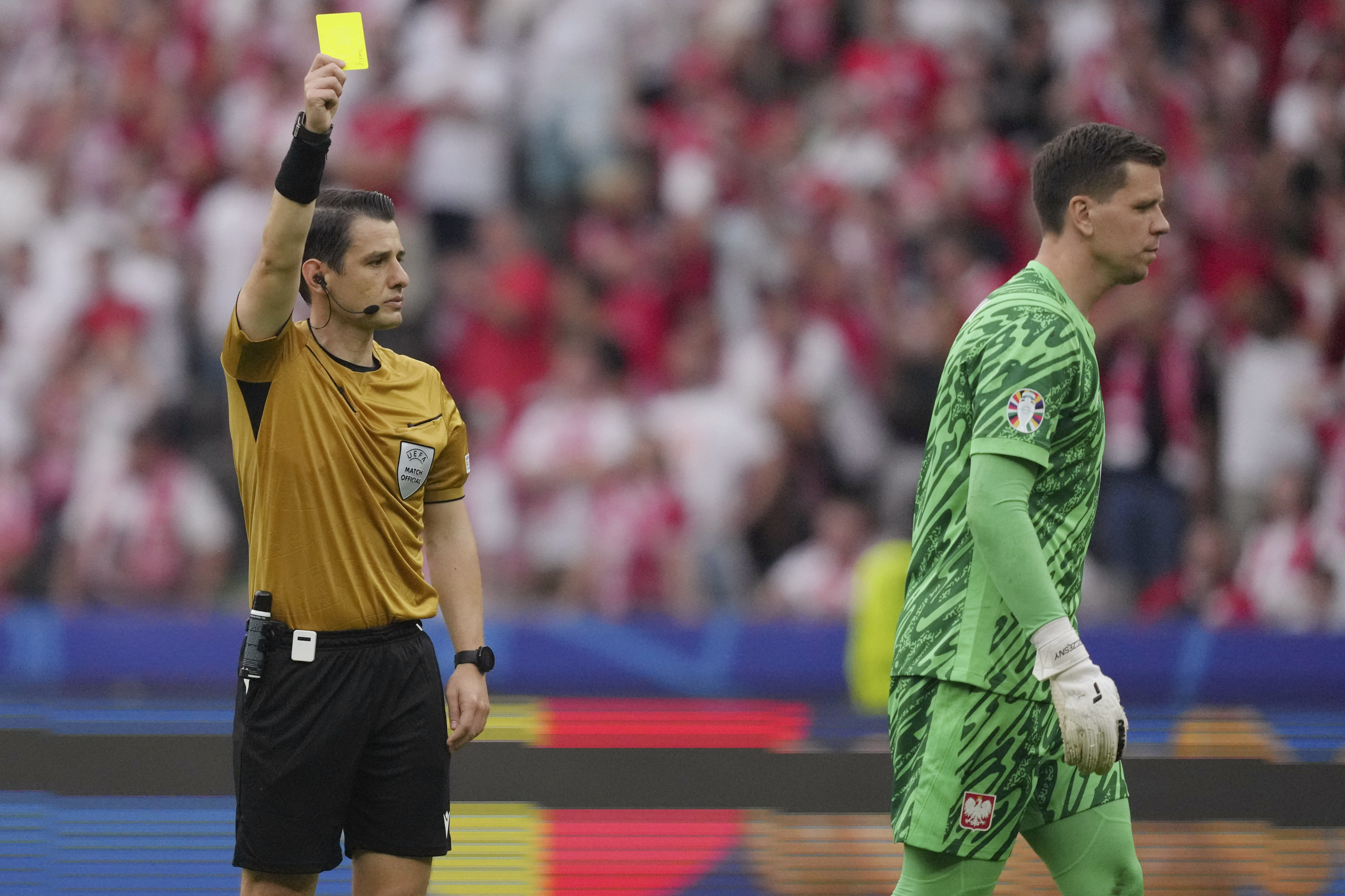 Referee Halil Umut Meler, of Turkey, issues a yellow card to Poland's goalkeeper Wojciech Szczesny during a Group D match between Poland and Austria at the Euro 2024 soccer tournament in Berlin, Germany, Friday, June 21, 2024. (AP Photo/Sunday Alamba)