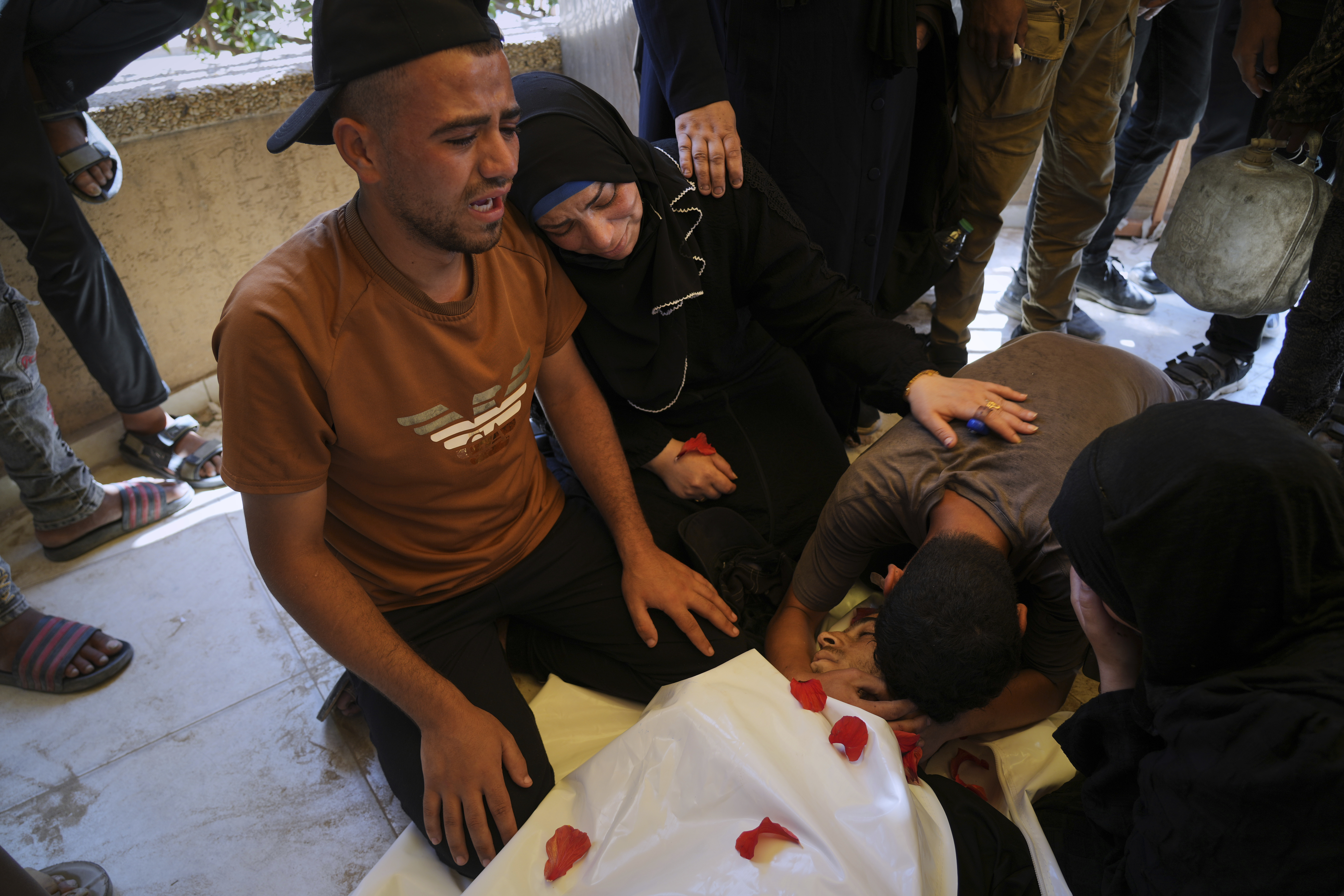 Palestinians mourn over the body of Ahmed Abu Hilal, who was killed while on his way to an aid hub in Gaza, during his funeral at Nasser Hospital in Khan Younis, in the southern Gaza Strip, on Sunday, June 8, 2025. [Abdel Kareem Hana/AP]