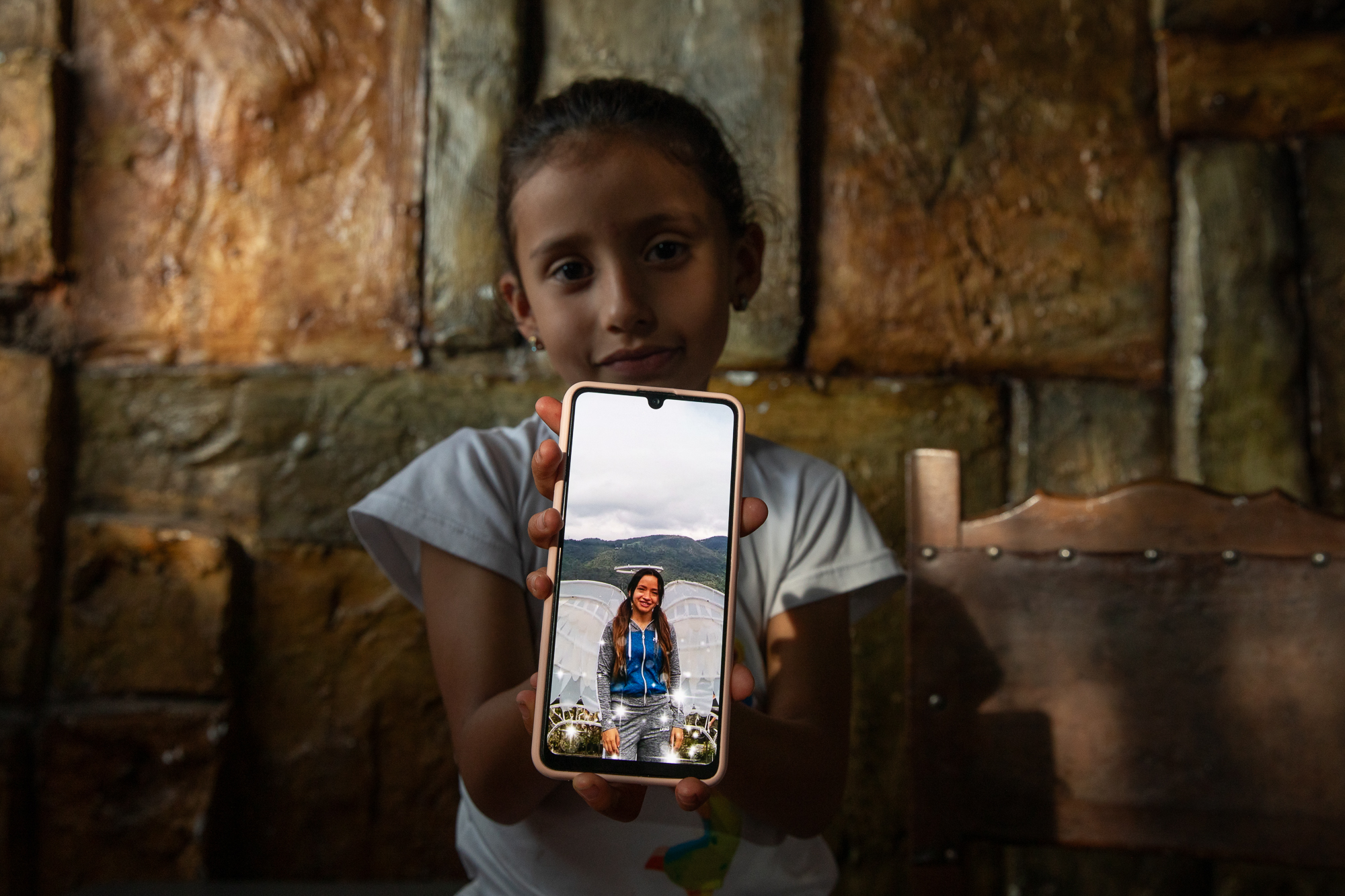 Luna Sofia Castro holds up a cellphone displaying a photograph of her deceased mother, Leidy Navarette.