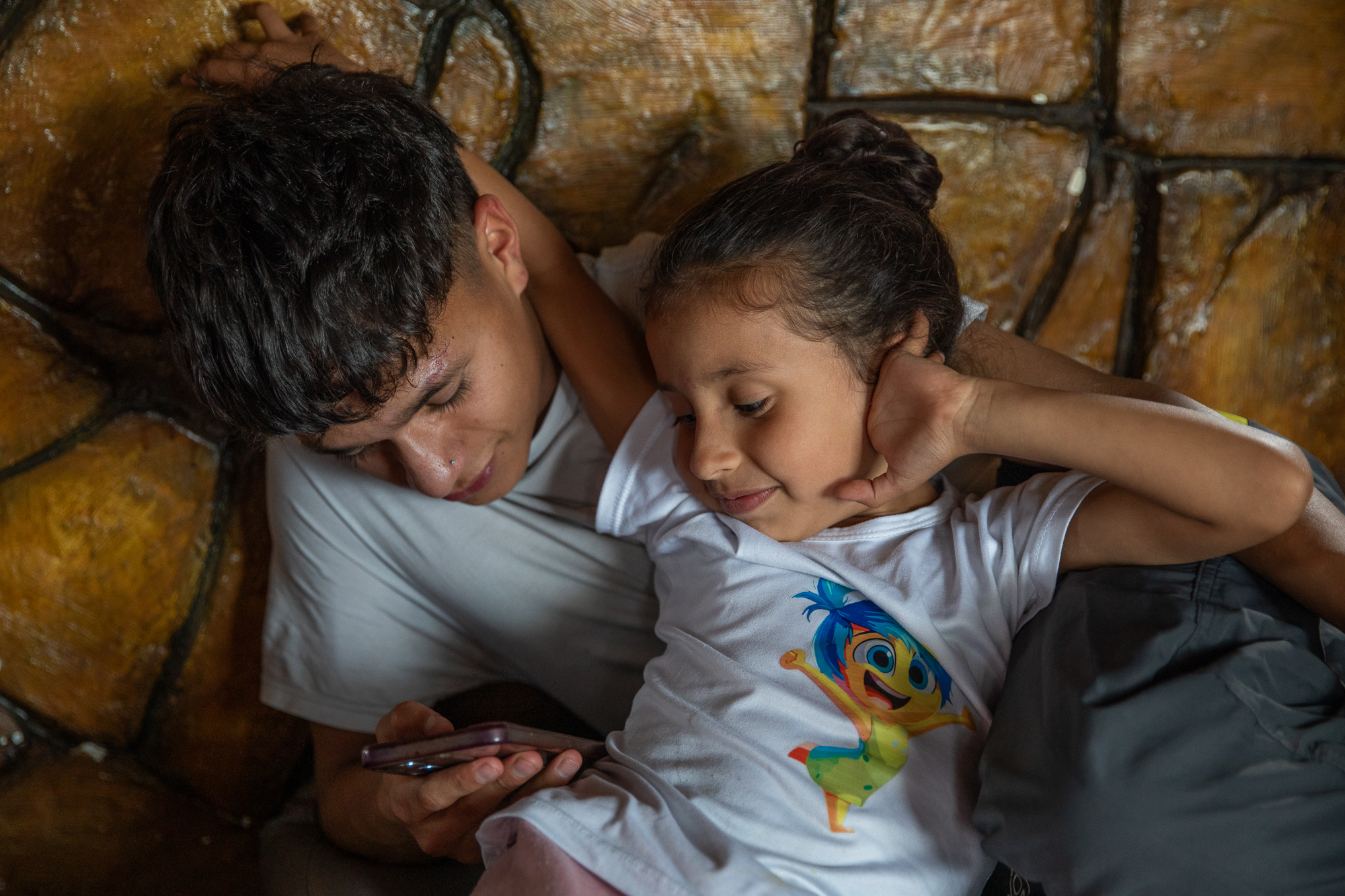 Fabian Ramirez reclines while he and his sister look at the cellphone in his hands.