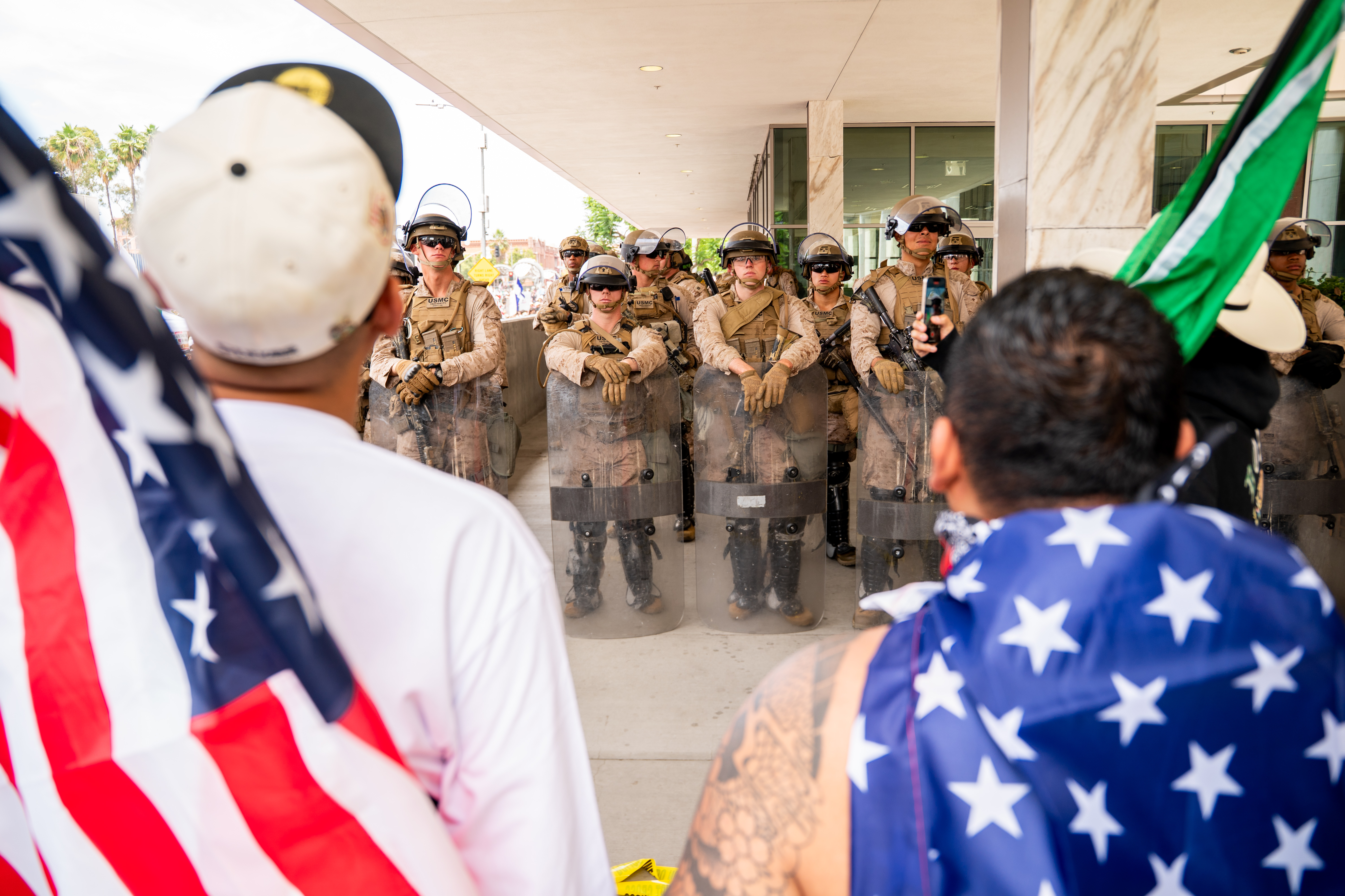 Law enforcement and Marines soldiers stand guard in a 'No Kings' protest.