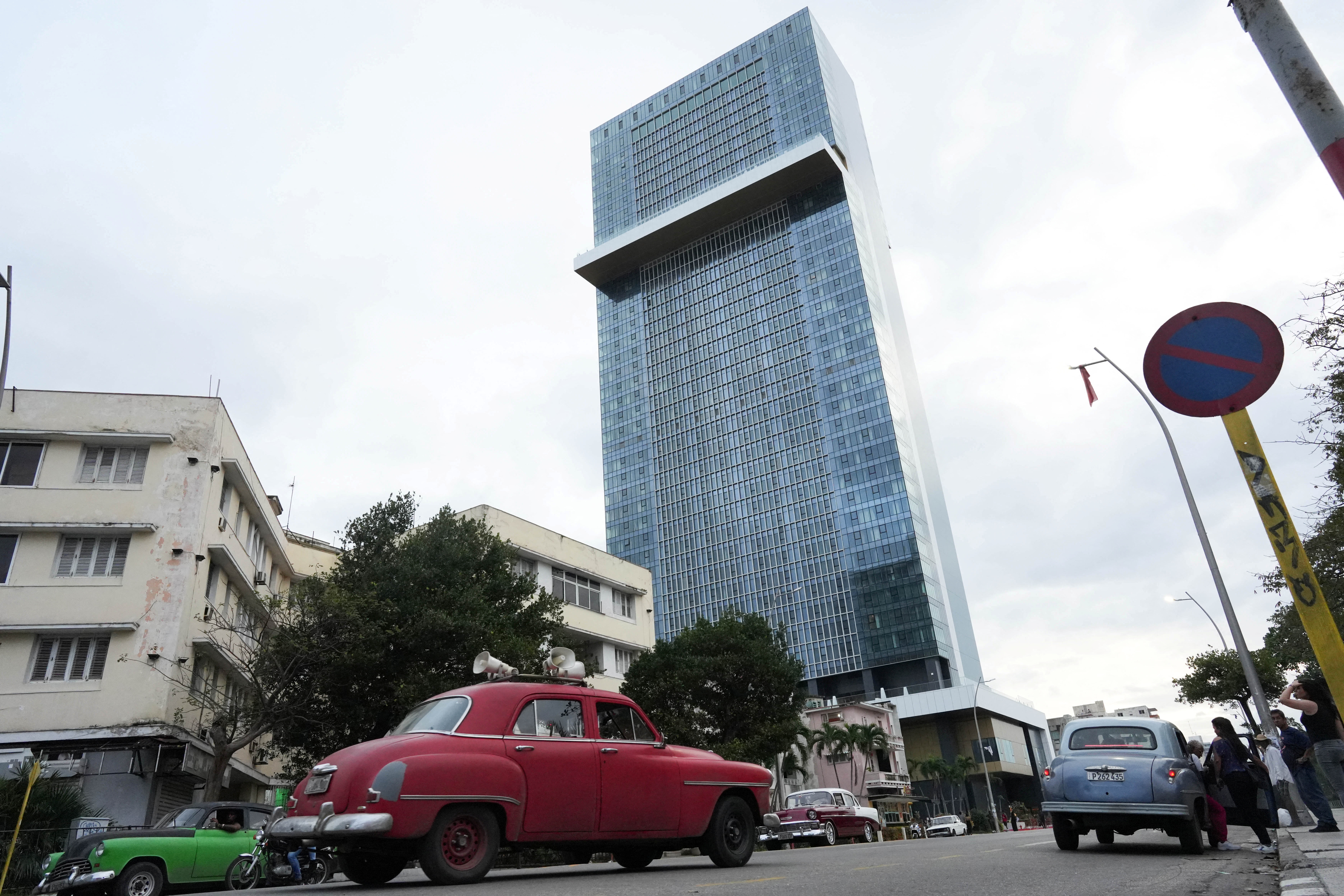 Vintage cars pass near the K23 Hotel in Havana, Cuba, December 28, 2024. REUTERS/Alexandre Meneghini