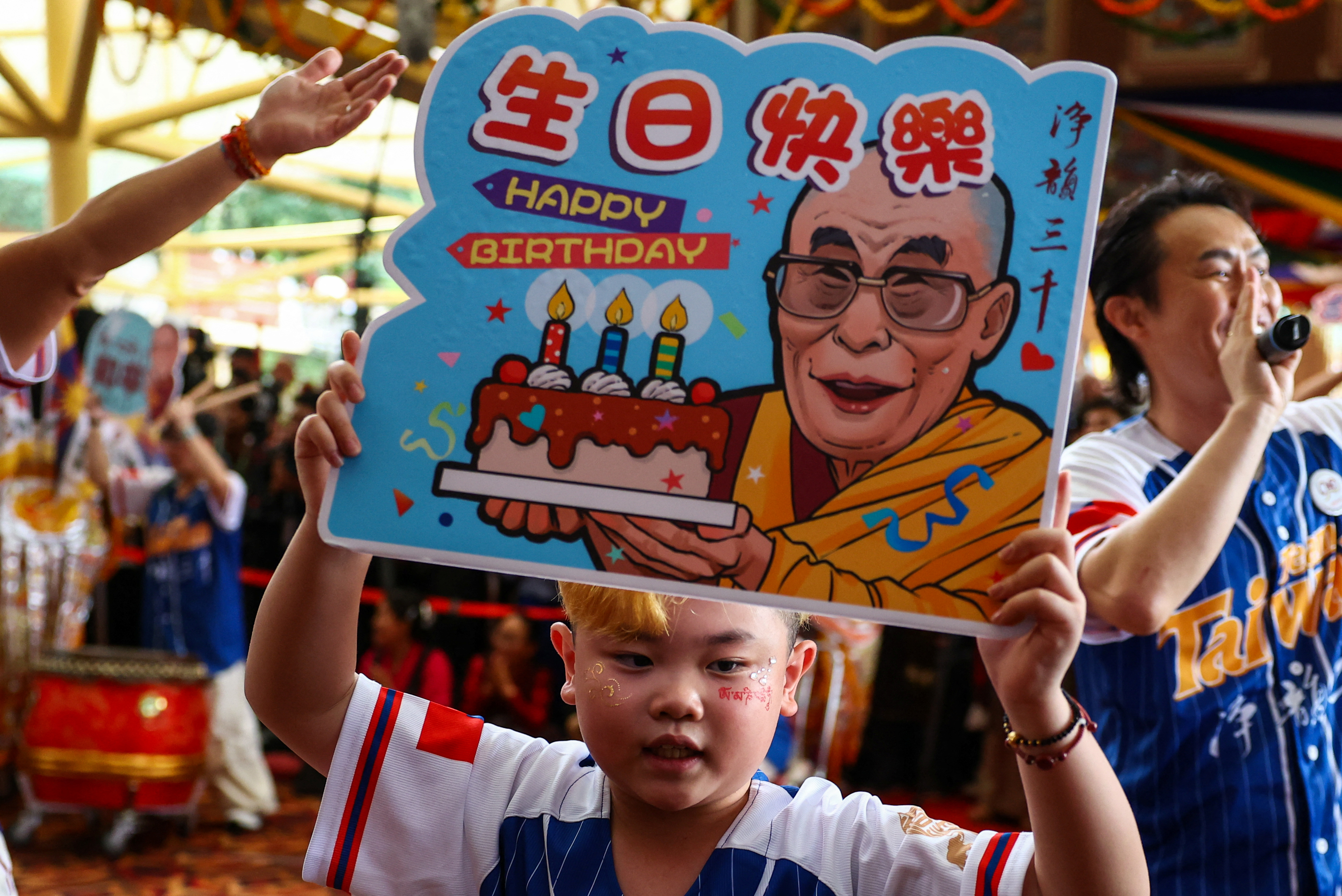 A child holds a placard on the 90th birthday of Tibetan spiritual leader, the 14th Dalai Lama, at the Tsuglagkhang, also known as the Dalai Lama Temple complex, in the northern town of Dharamshala, India