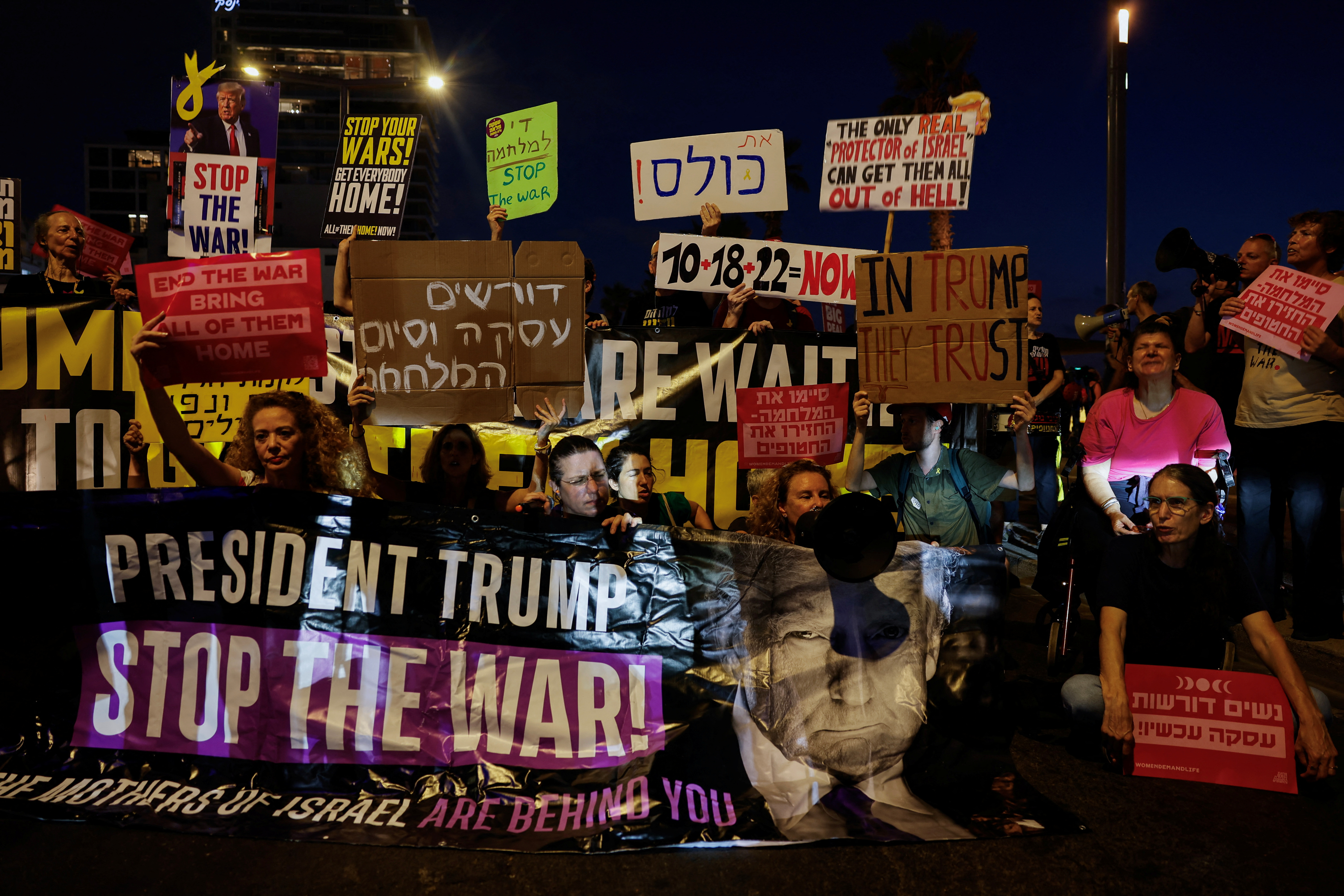 Demonstrators hold a banner featuring an image of U.S. President Donald Trump, during a protest to demand the immediate release of all hostages held in Gaza.