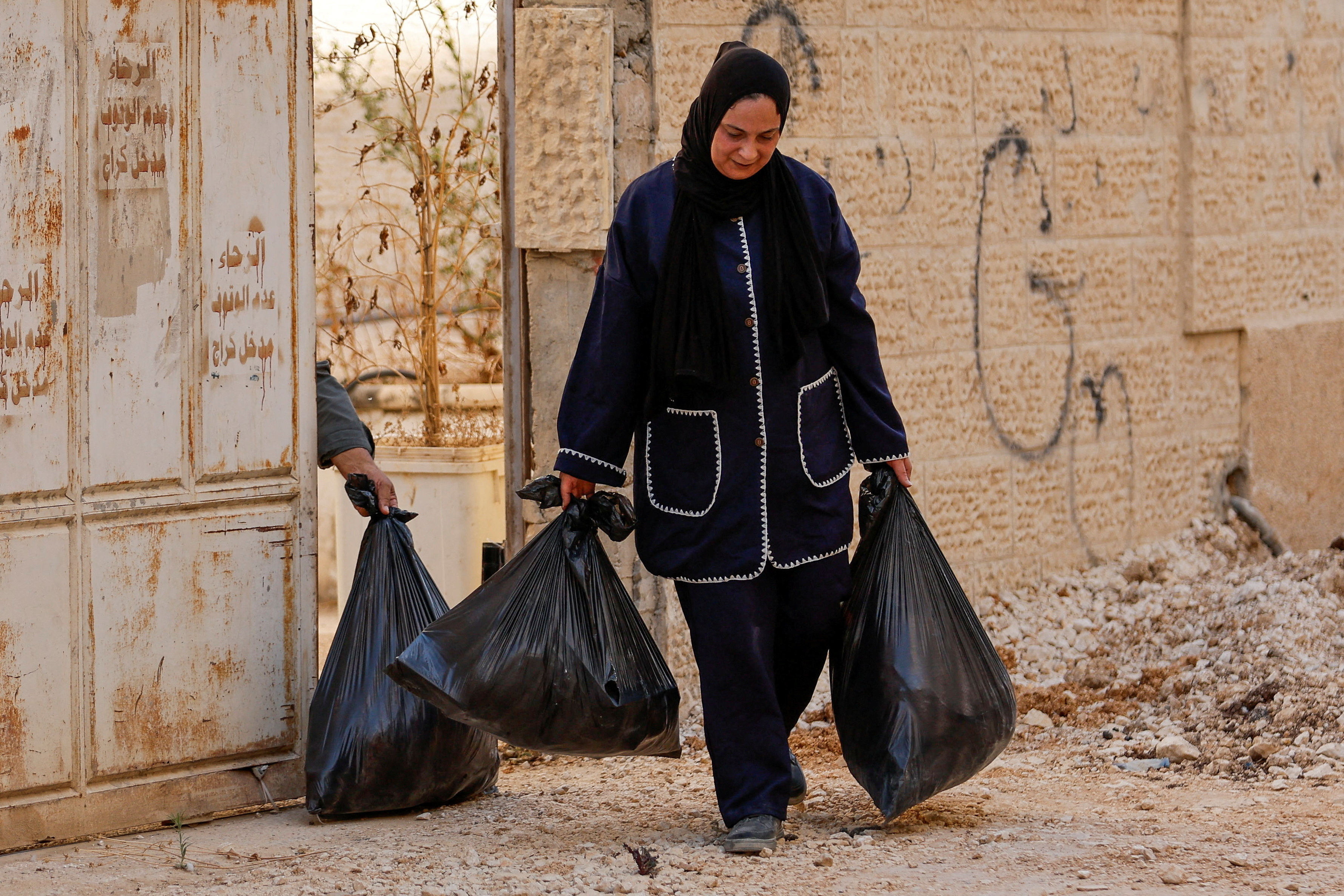 soldiers watch as people carry their belongings
