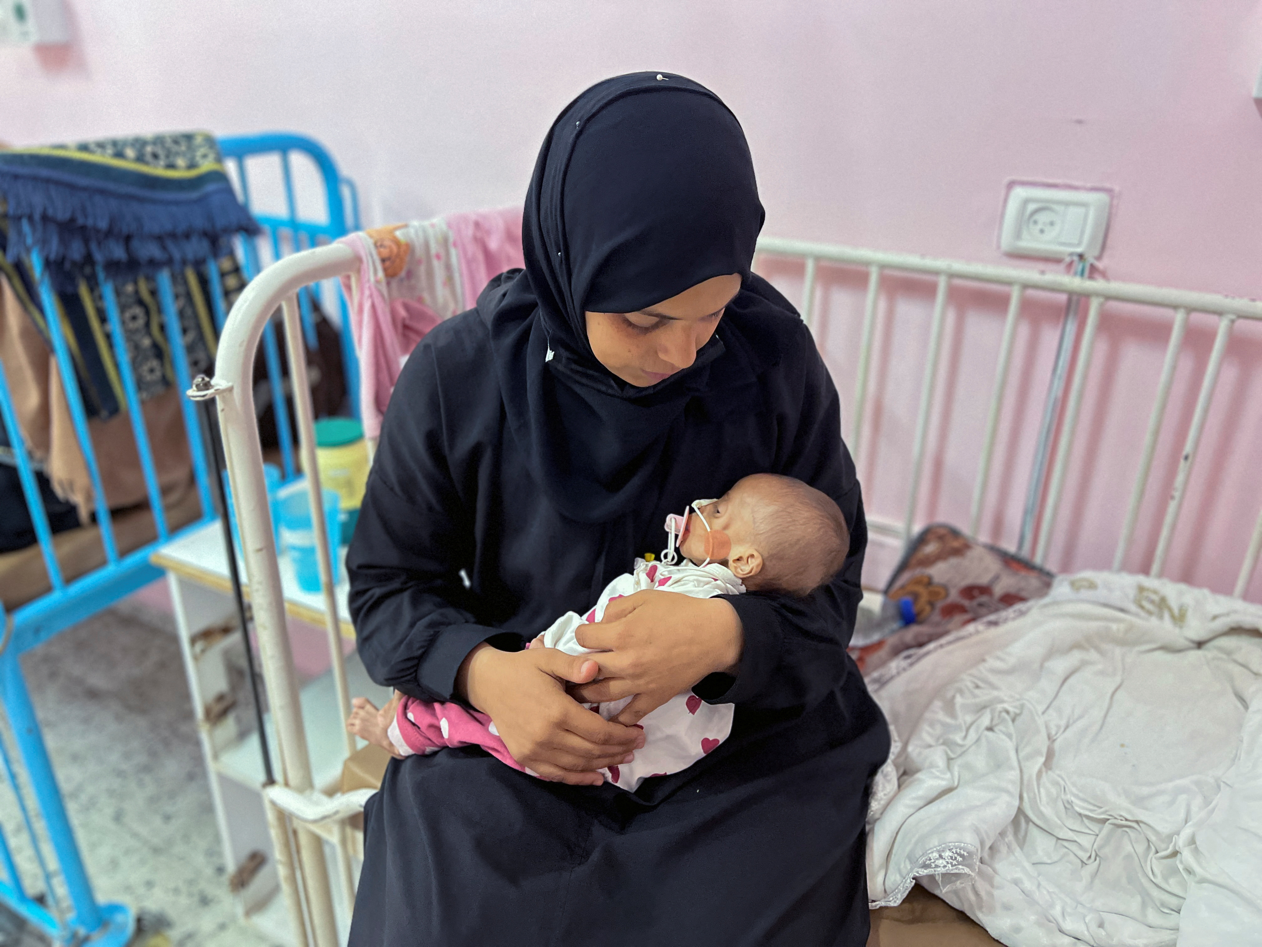 Palestinian mother Israa Abu Haleeb looks after her five-month-old daughter, Zainab, who is diagnosed with malnutrition, according to medics, at Nasser hospital in Khan Younis [File: Hussam Al-Masri/Reuters]