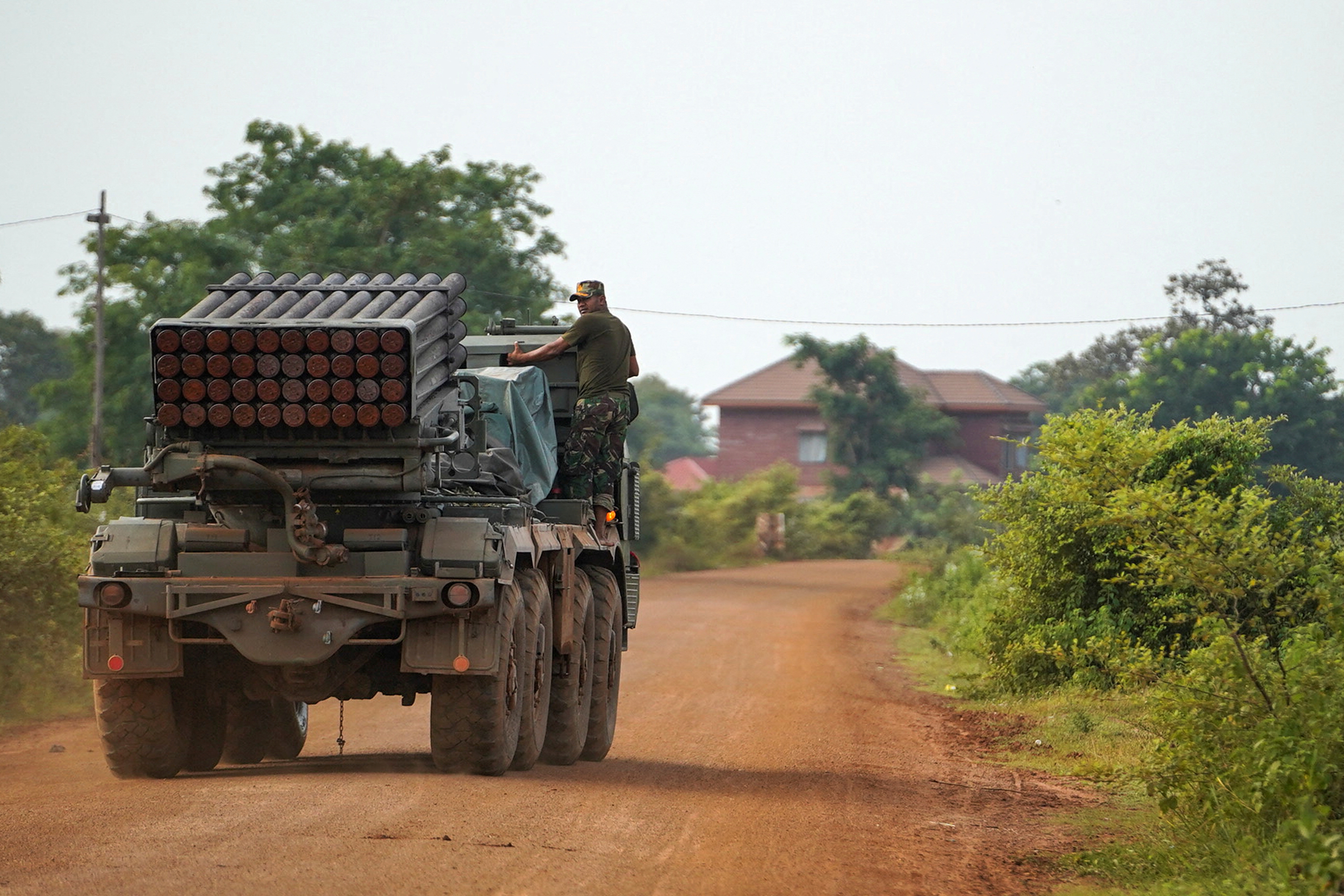 A Cambodian military personnel member stands on a rocket launcher.