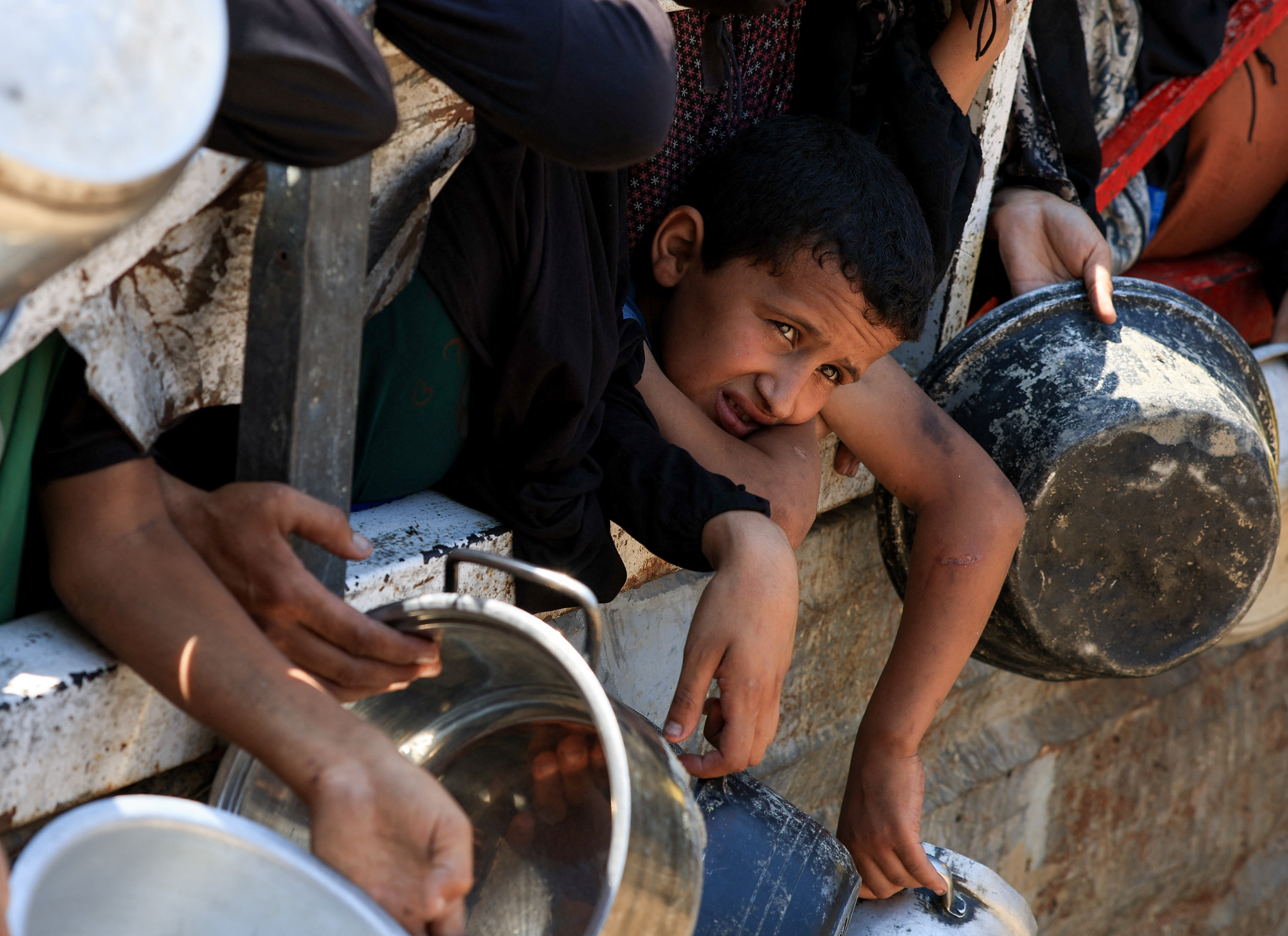 A Palestinian boys looks on as he tries to get food in Gaza