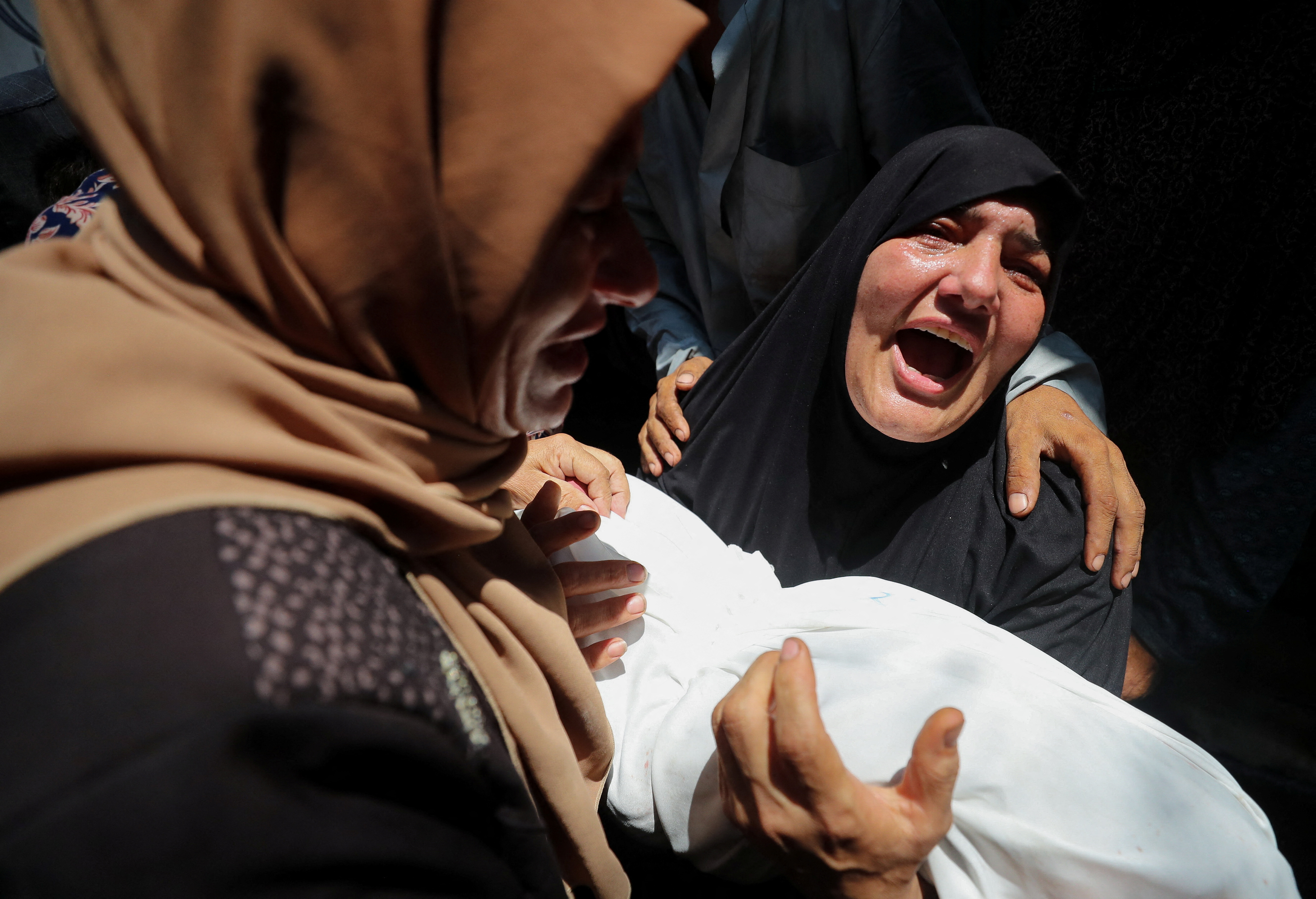 A woman mourns a child in her arms.