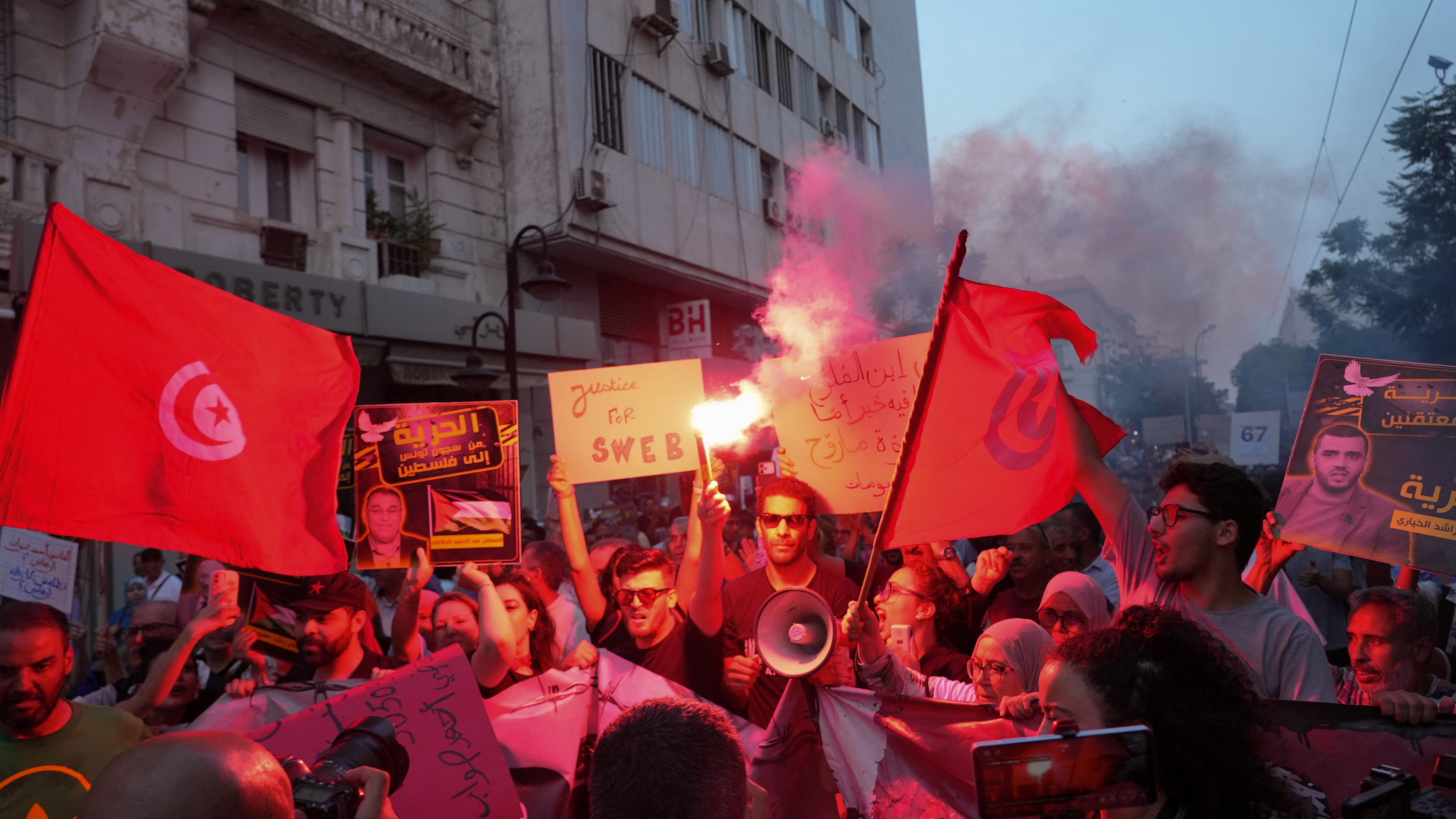 A man holds a flare as protesters rally.