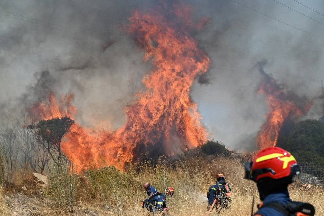 Firefighters try to extinguish flames as a wildfire burns on the island of Kythira
