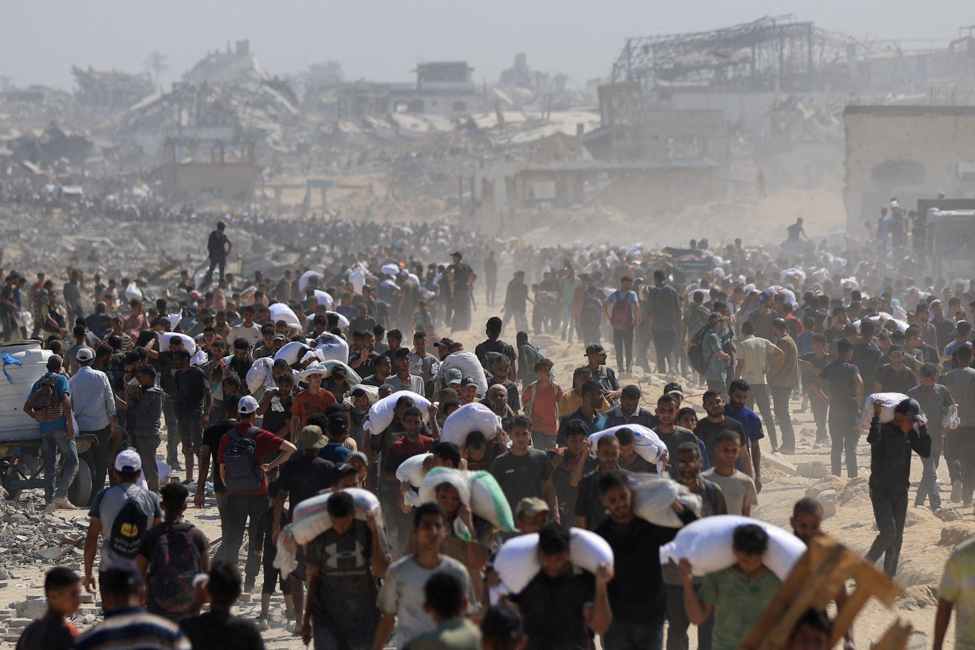 Palestinians carry aid supplies that entered Gaza through Israel, in Beit Lahia in the northern Gaza Strip, July 27, 2025. [Dawoud Abu Alkas/Reuters]