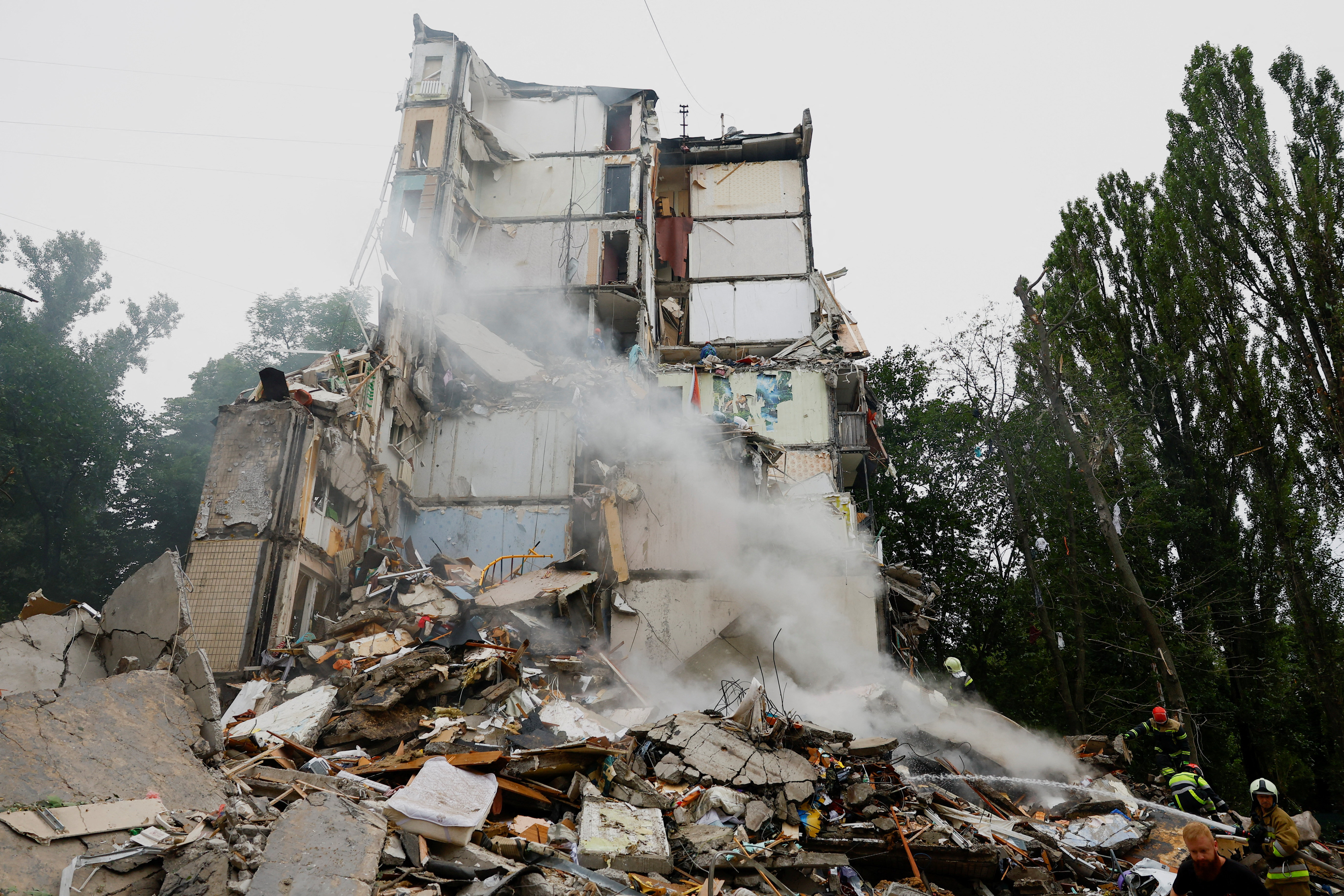 Rescuers work at the site of a damaged apartment building.