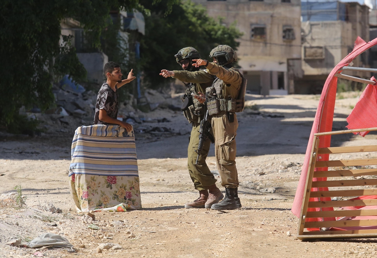soldiers in a street talk to a young man