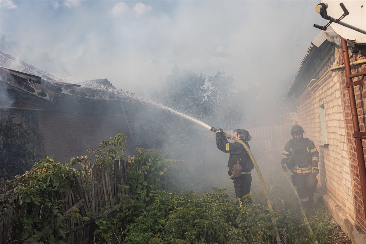 a firefighter hoses a house surrounded by smoke