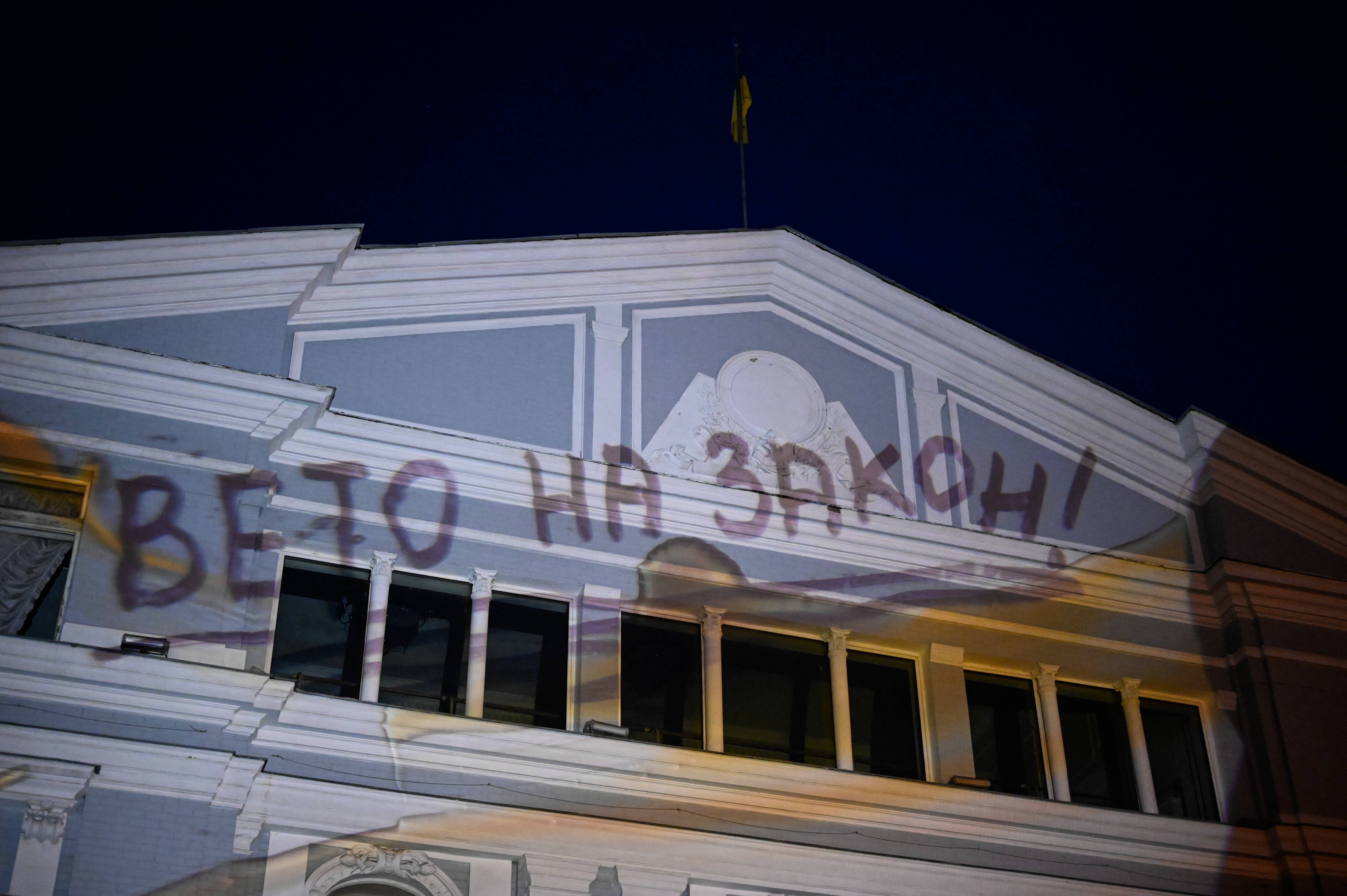 The building Ivan Franko National Theather of Ukraine is seen as the slogan "Veto the law" is projected onto it as Kyiv residents take part in a rally against the implementation of Zelenskyy's new law that curbs anticorruption agencies.