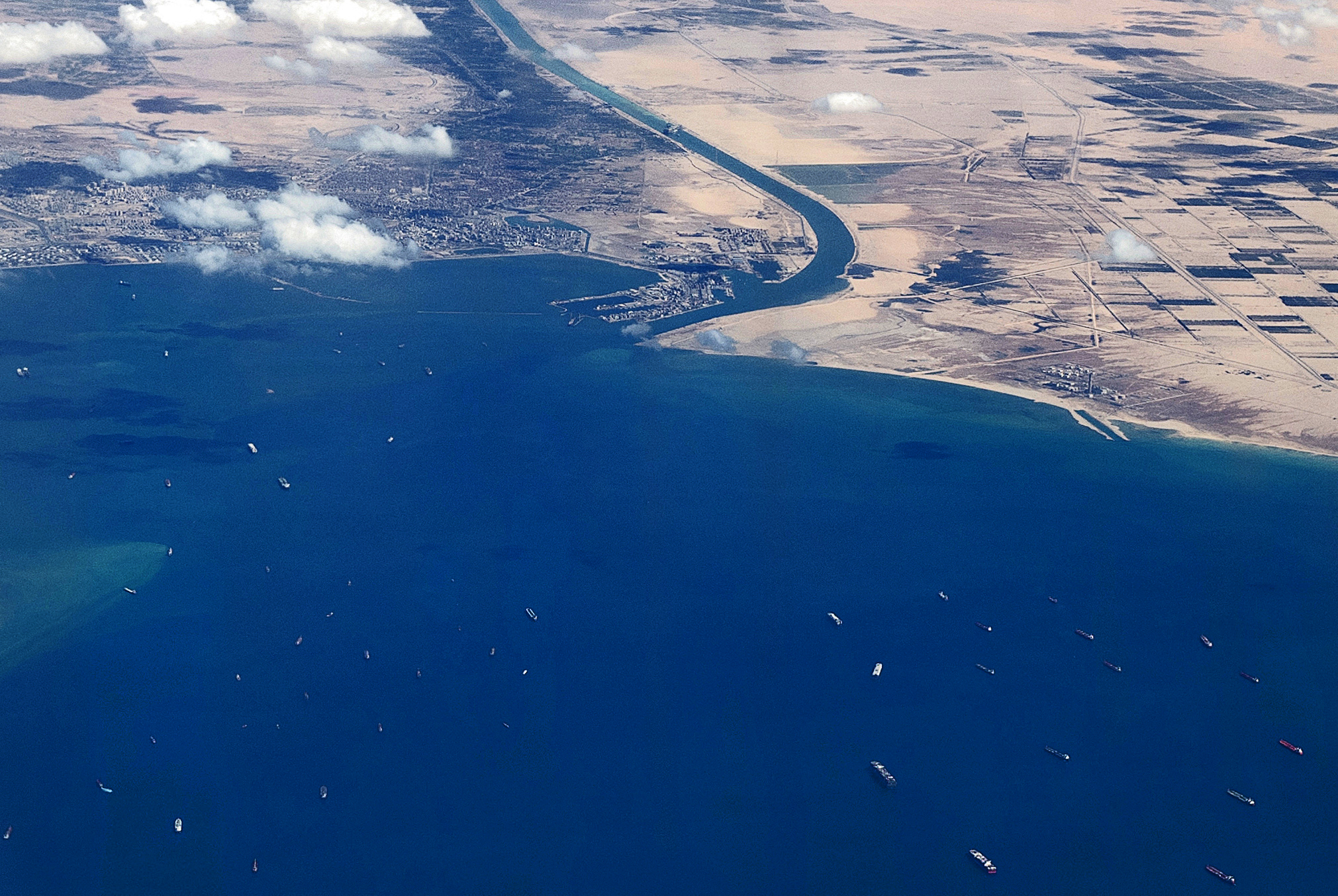 An aerial view taken on March 27, 2021 from the porthole of a commercial plane shows stranded ships waiting in queue in the Gulf of Suez to cross the Suez Canal at its southern entrance near the Red Sea port city of Suez.