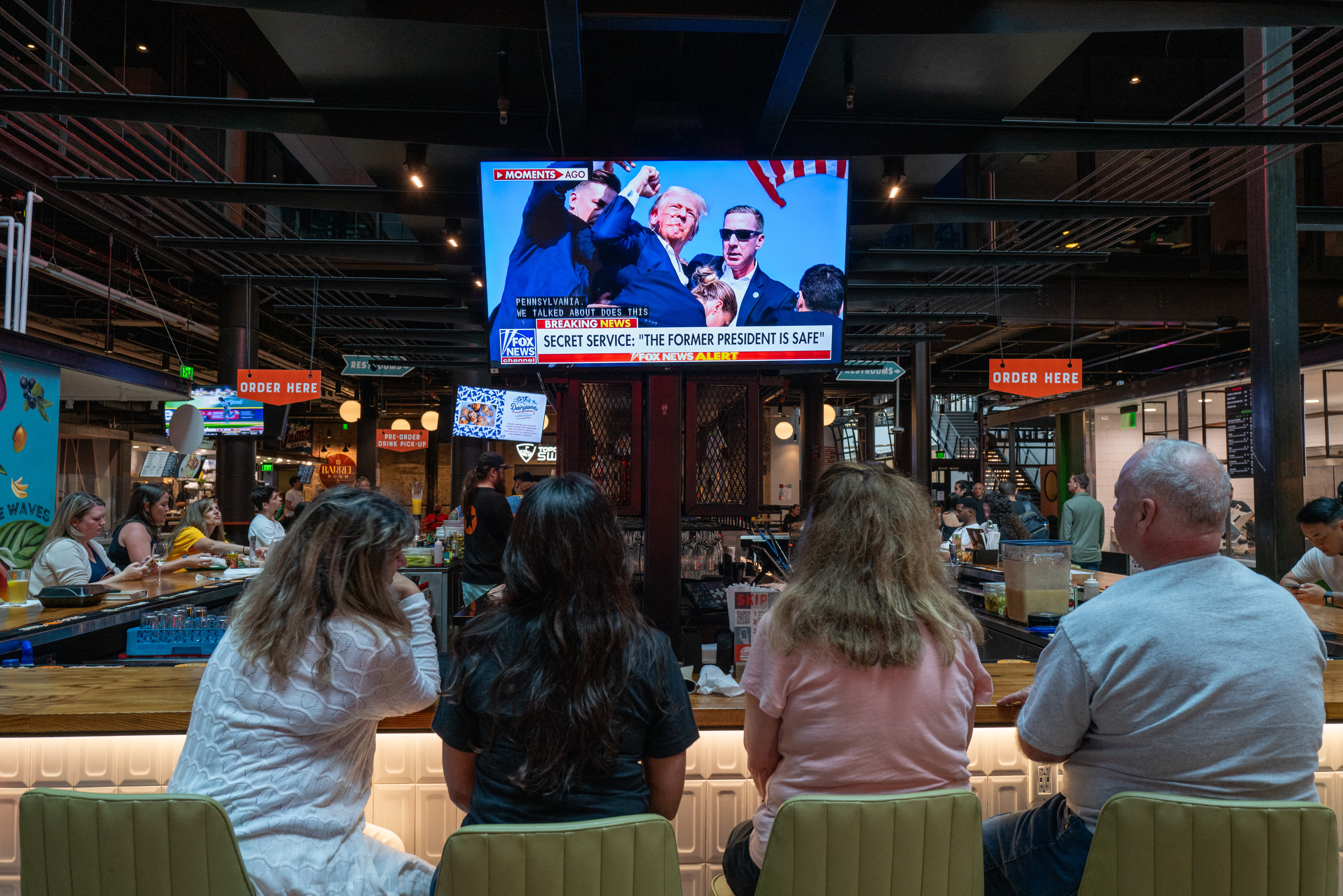 MILWAUKEE, WISCONSIN - JULY 13: People watch television news at a bar in Milwaukee displaying images from a campaign rally for former U.S. President Donald Trump where he was apparently injured on July 13, 2024 in Milwaukee, Wisconsin. Details are unclear, but Secret Service quickly ushered Trump away while speaking at the Pennsylvania rally. Spencer Platt/Getty Images/AFP (Photo by SPENCER PLATT / GETTY IMAGES NORTH AMERICA / Getty Images via AFP)
