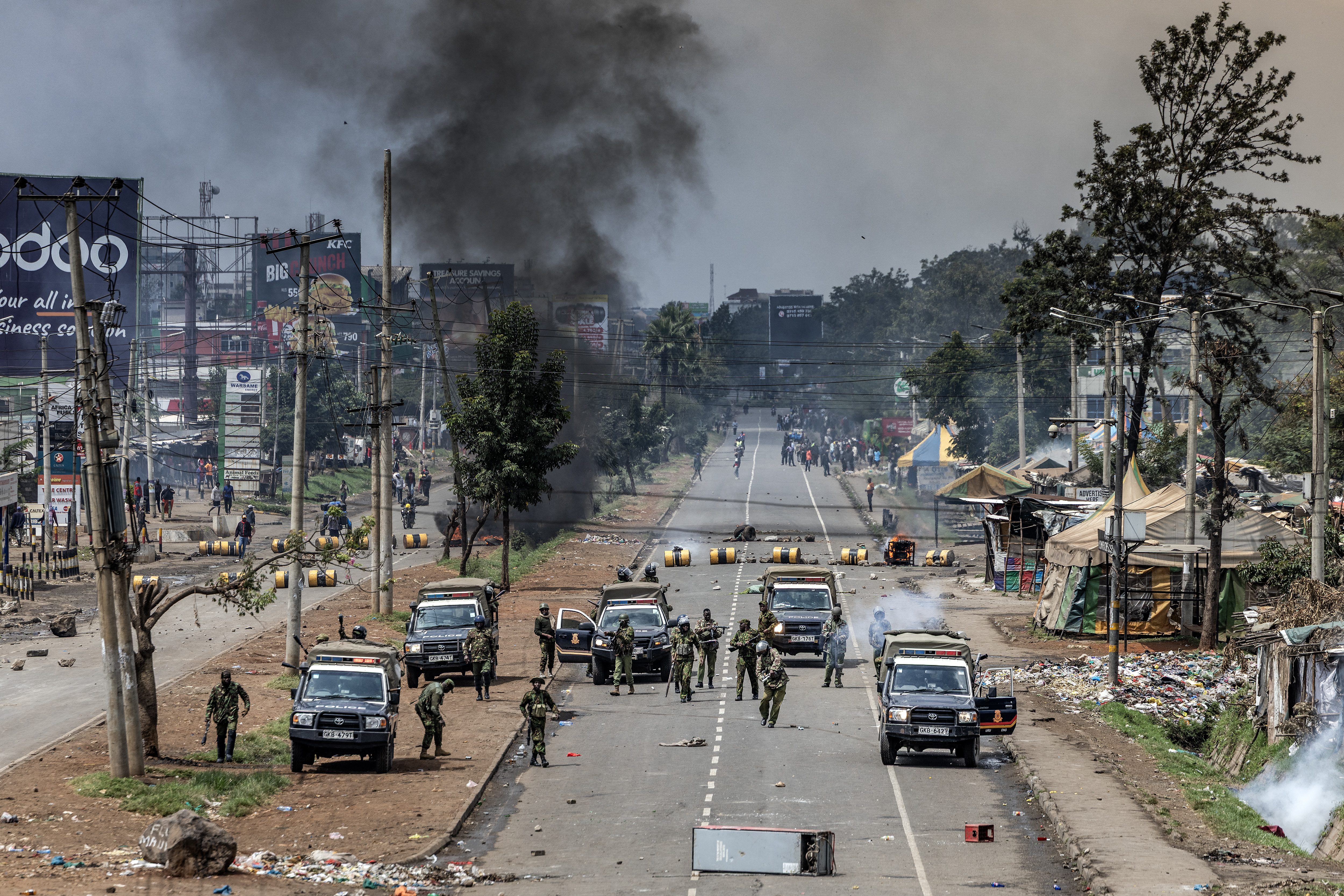 smoke rises in the distance as police block a road