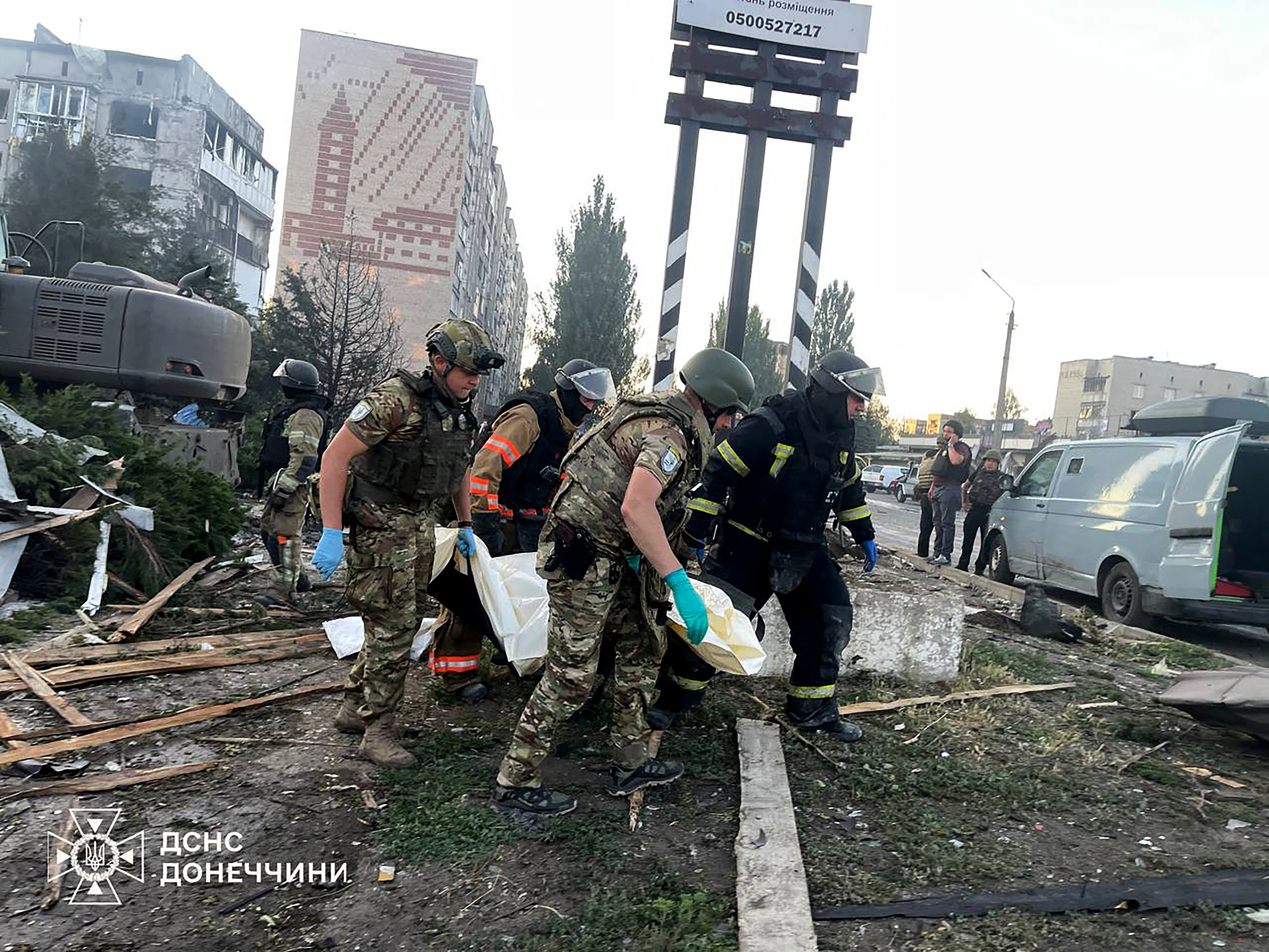 This handout picture taken and released by Ukrainian State Emergency Service on July 16, 2025 shows rescuers carrying a body from a damaged civilian installation following a Russian strike in Dobropillia, Donetsk region, amid Russian invasion in Ukraine. A Russian strike on a central square in Ukraine's frontline town of Dobropillia killed at least two people and wounded 22, authorities said on July 16, 2025 in a new blow to US President Donald Trump's calls for Moscow to end its invasion. (Photo by Handout / Ukrainian State Emergency Service / AFP) / RESTRICTED TO EDITORIAL USE - MANDATORY CREDIT "AFP PHOTO / HANDOUT / UKRAINIAN EMERGENCY SERVICE" - NO MARKETING NO ADVERTISING CAMPAIGNS - DISTRIBUTED AS A SERVICE TO CLIENTS