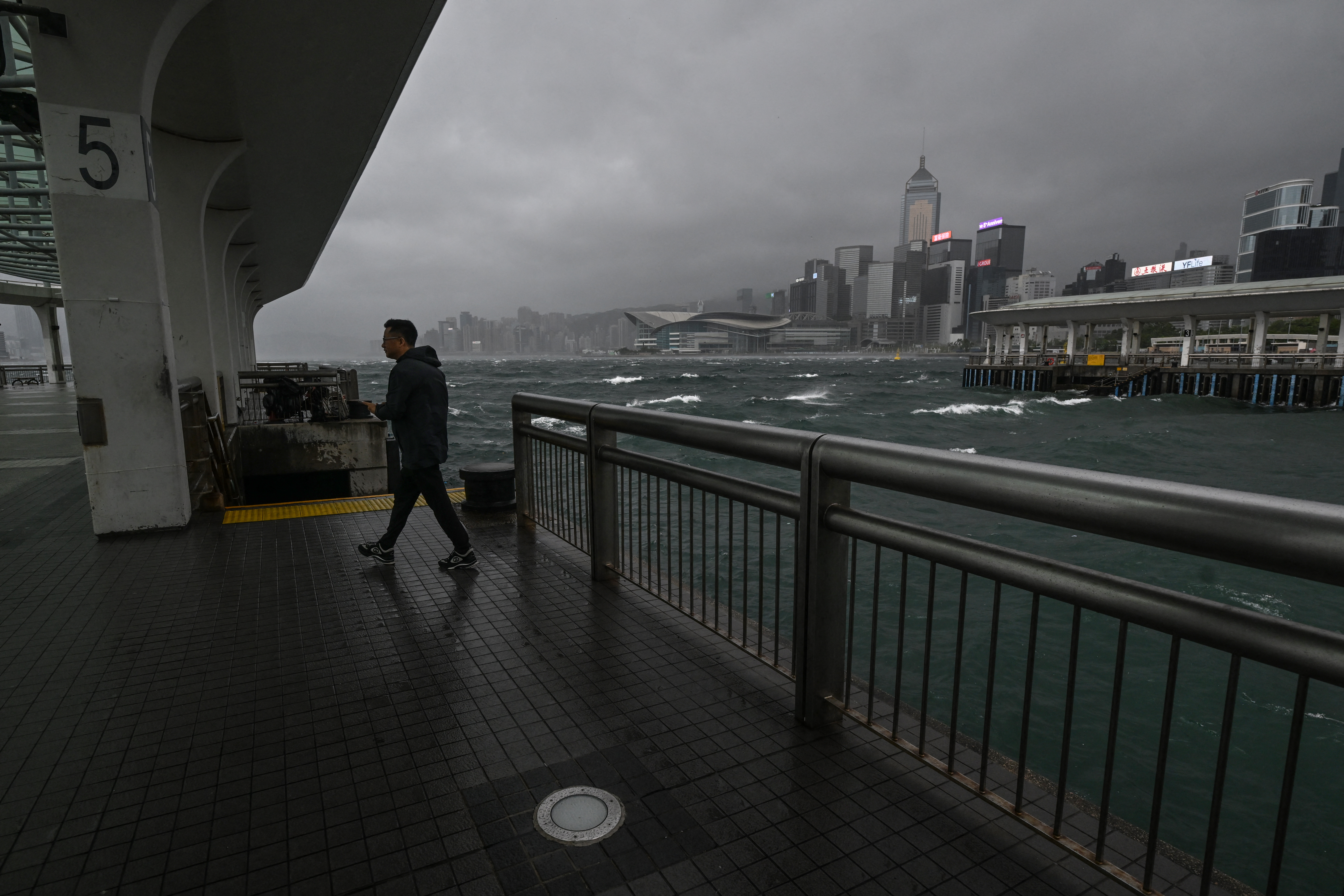 A man walks on a pier while dark clouds gather and rough seas are seen in Victoria harbour as the typhoon signal number 10 is hoisted as Typhoon Wipha moves towards Hong Kong