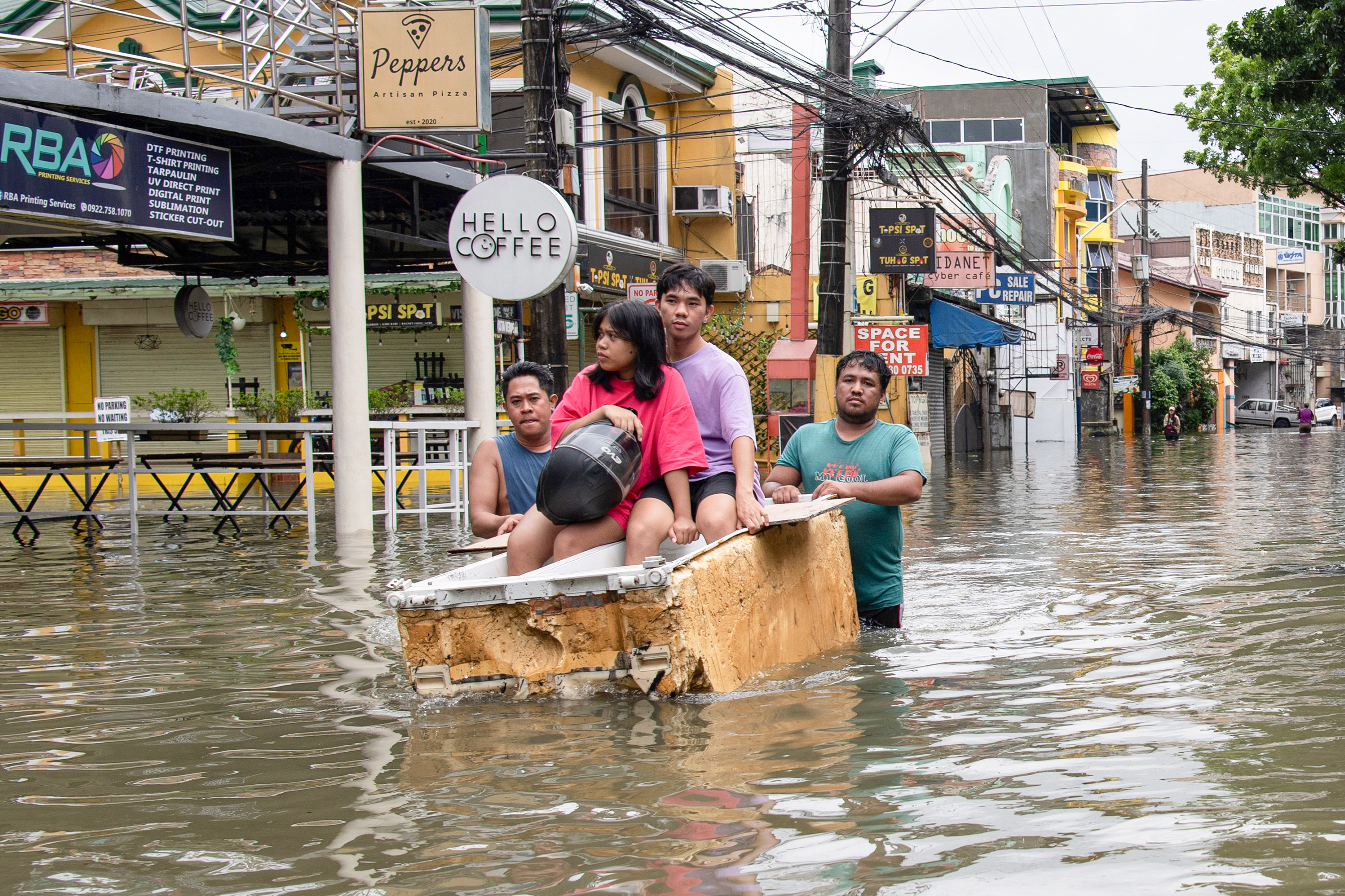 People ride on makeshift raft at a village in Cainta town, east of Manila