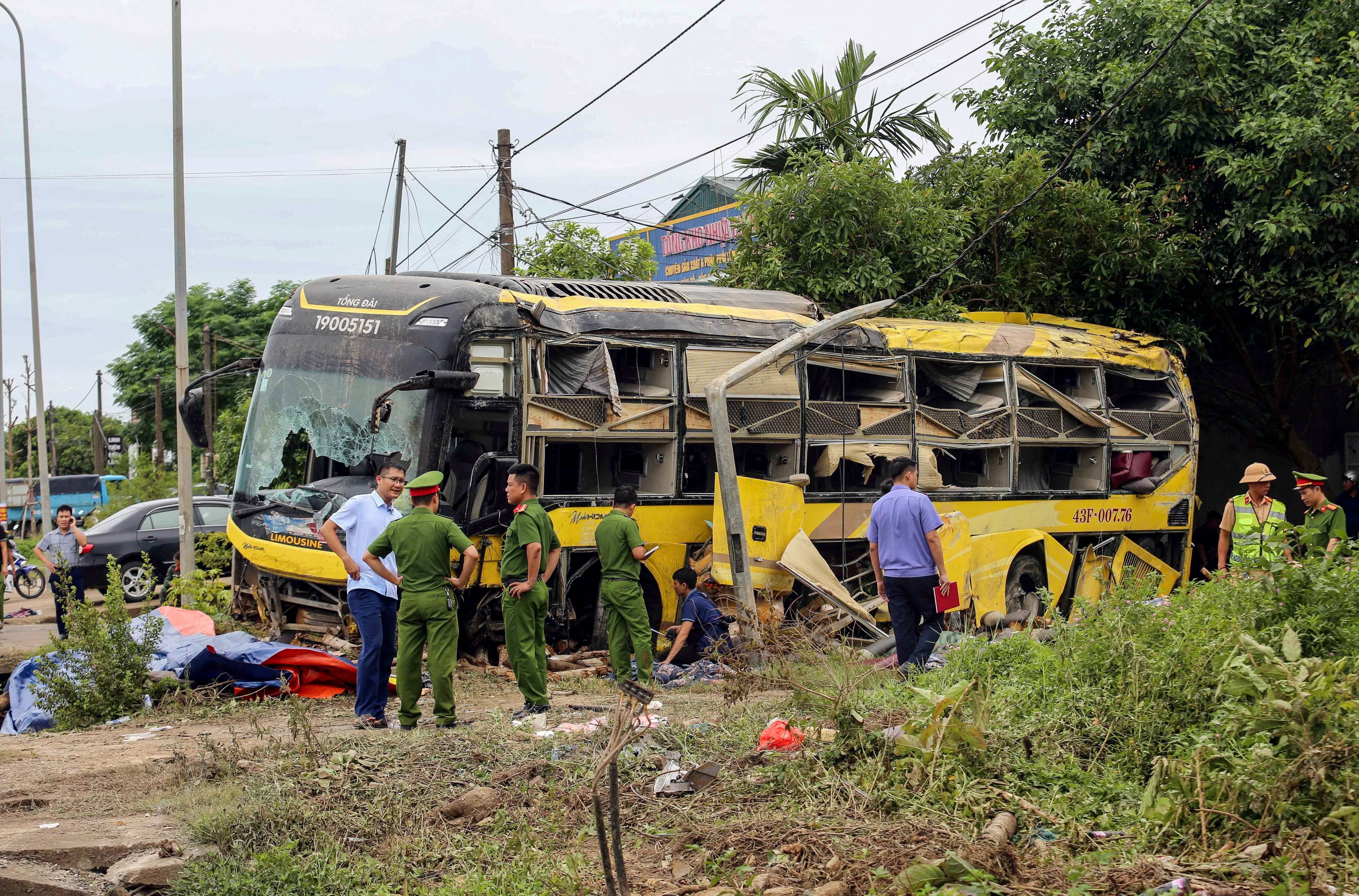 This handout photograph taken and released by the Vietnam News Agency (VNA) on July 25, 2025 shows security personnel along with authorities standing next to a crashed bus in Ha Tinh province, Central Vietnam. Ten people were killed in central Vietnam in a bus crash early on July 25, a week after dozens of tourists died in a boat accident in Ha Long Bay. (Photo by Vietnam News Agency / AFP) / RESTRICTED TO EDITORIAL USE - MANDATORY CREDIT "AFP PHOTO/VIETNAM NEWS AGENCY (VNA)/-" - HANDOUT - NO MARKETING NO ADVERTISING CAMPAIGNS - DISTRIBUTED AS A SERVICE TO CLIENTS