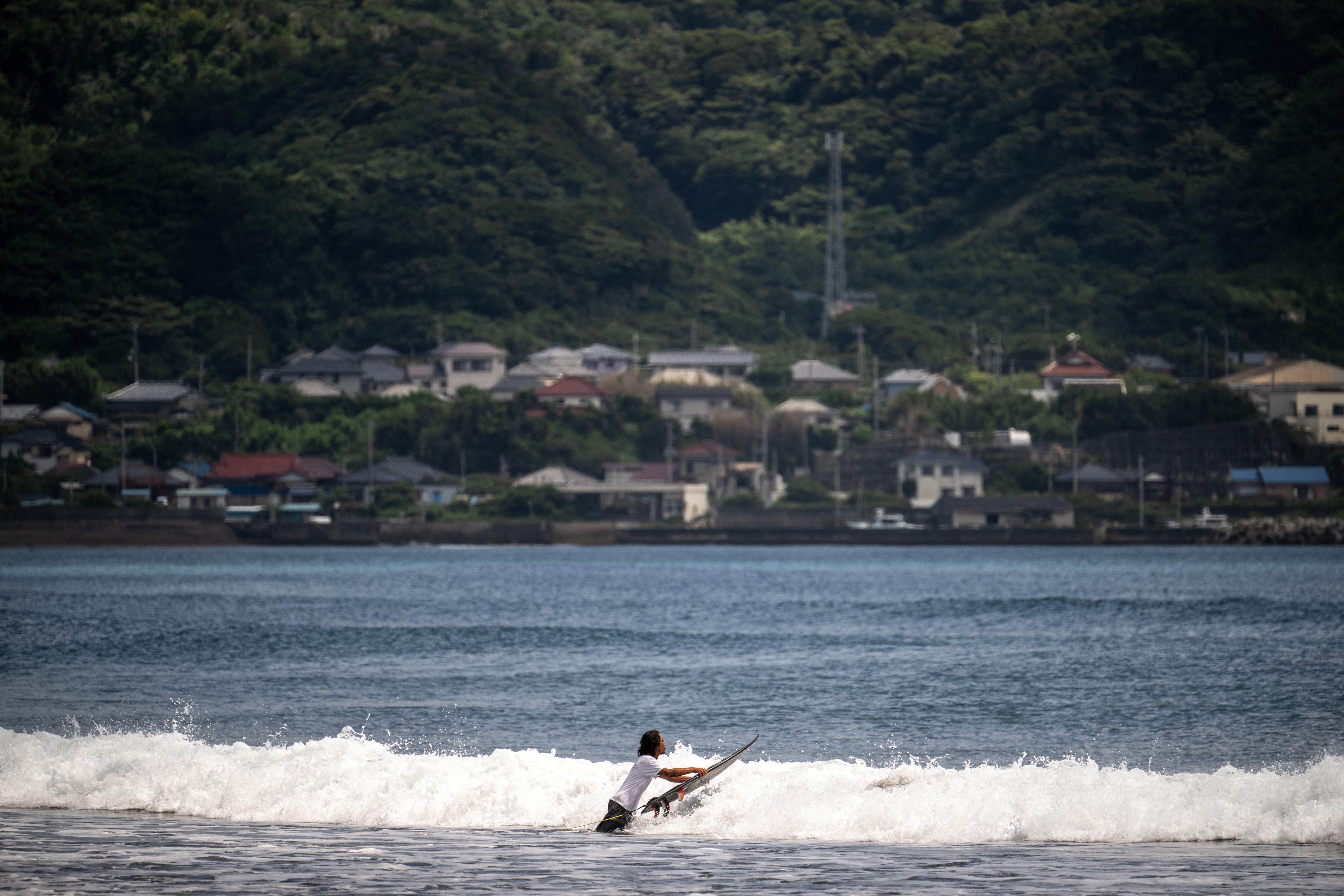 A man prepares to surf from Heisaura Beach in the city of Tateyama of Chiba Prefecture after the tsunami advisory was lifted on July 31, 2025. (Photo by Philip FONG / AFP)