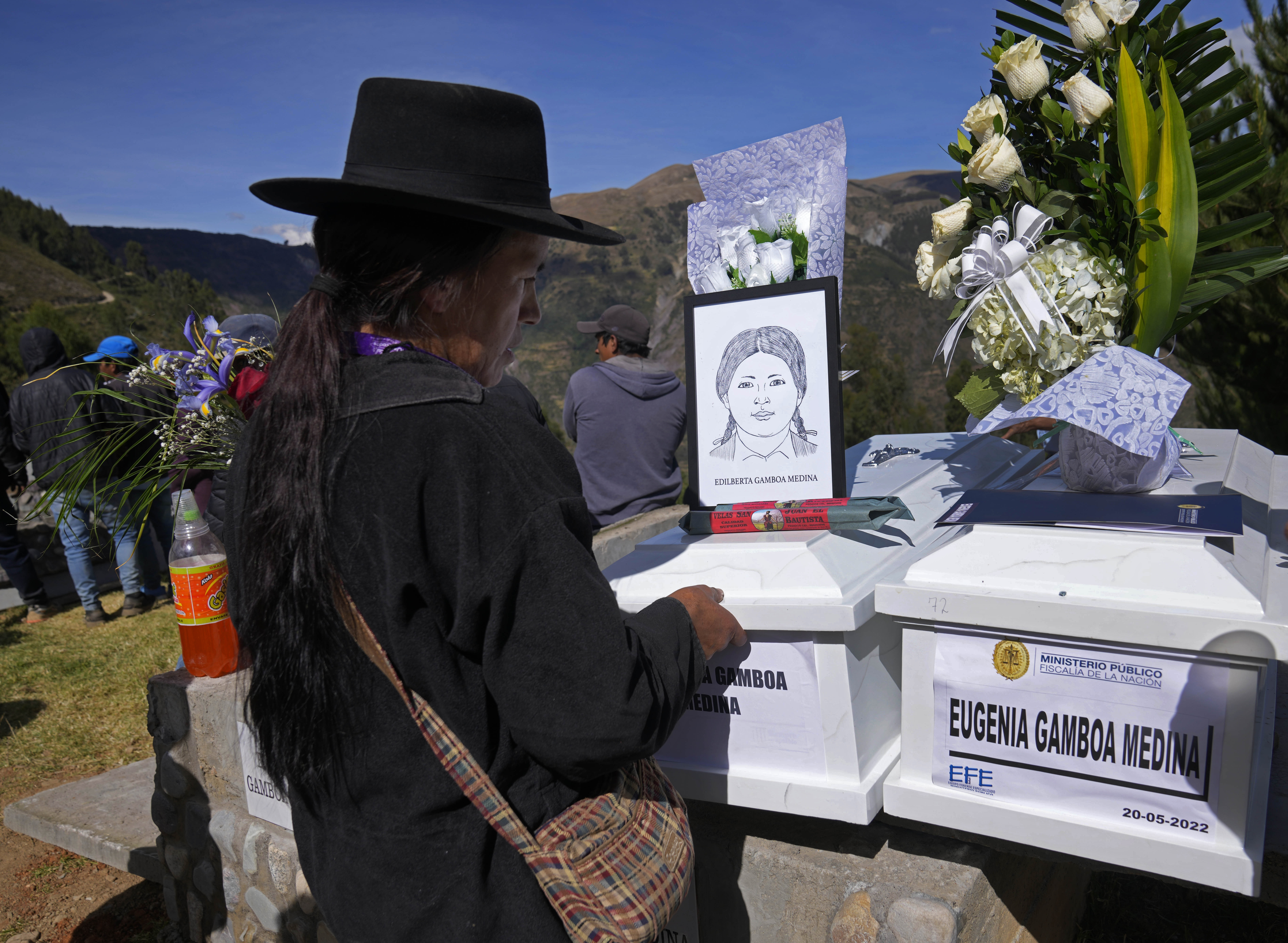 A mourner stands in front of a white coffin representing her sister.