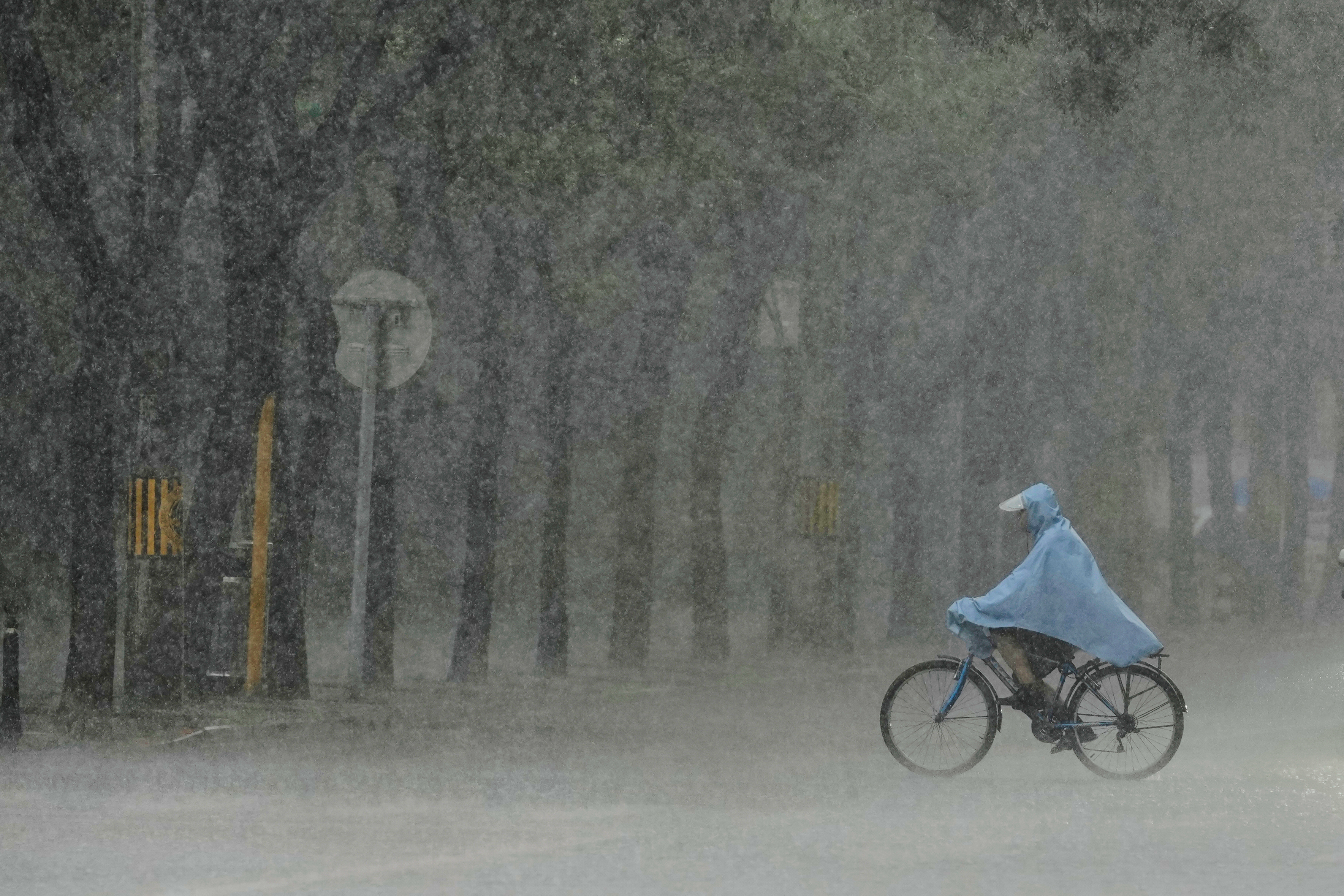 A man rides a bicycle during heavy rain in Beijing