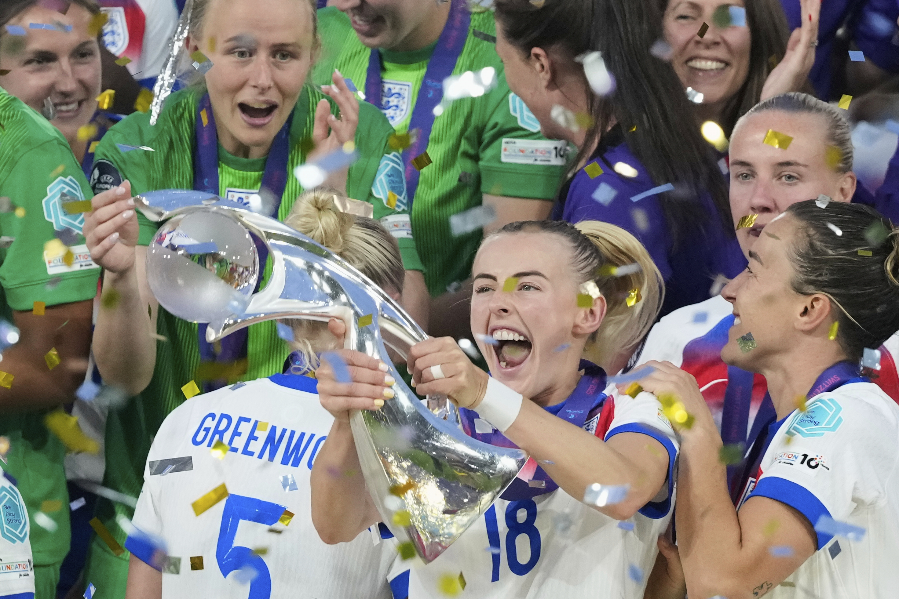 England's Chloe Kelly celebrates with the trophy as goalkeeper Hannah Hampton at left looks on after winning the Women's Euro 2025 final soccer match between England and Spain at St. Jakob-Park in Basel, Switzerland, Sunday, July 27, 2025. (AP Photo/Alessandra Tarantino)