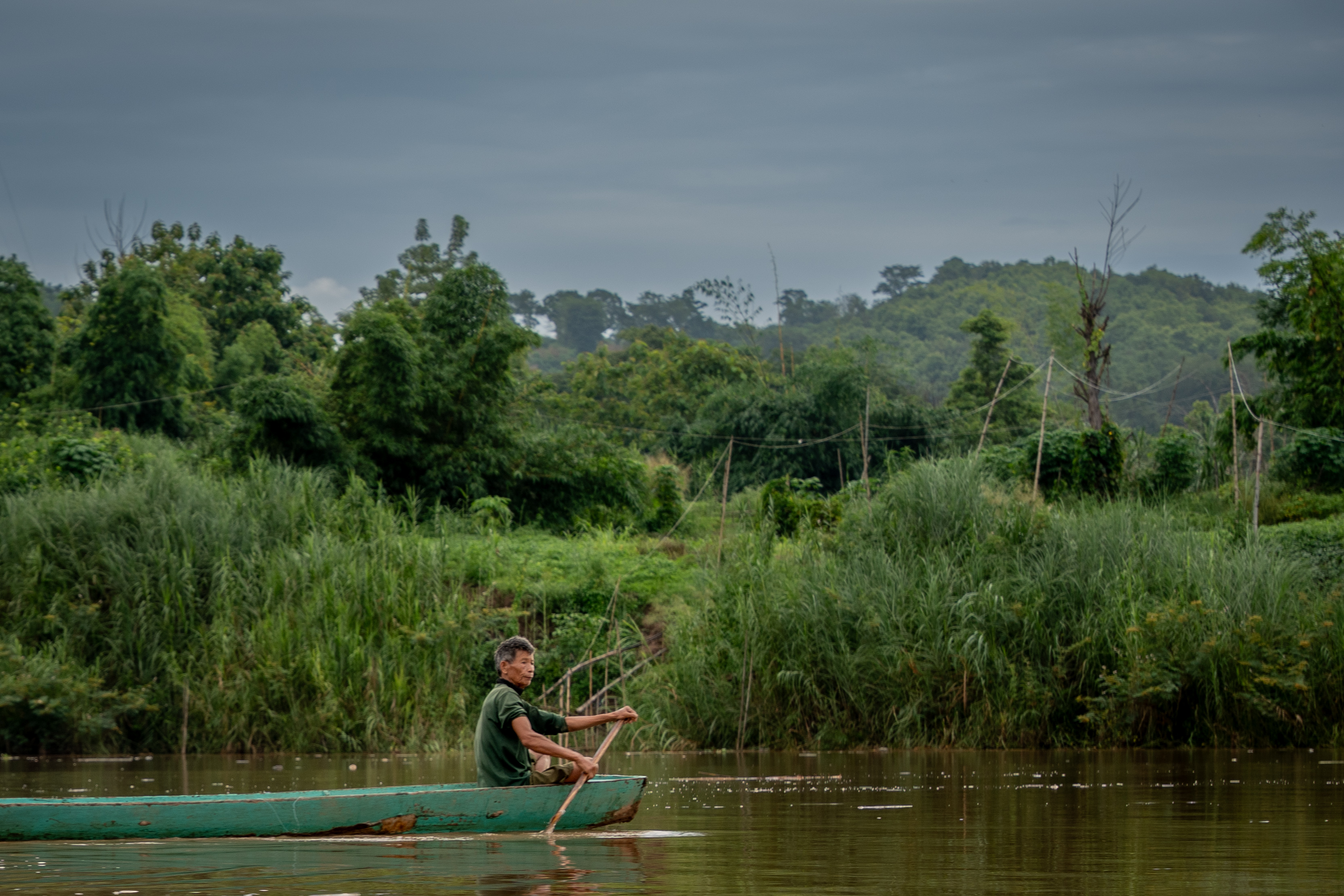 A fisherman guides his boat along a river.