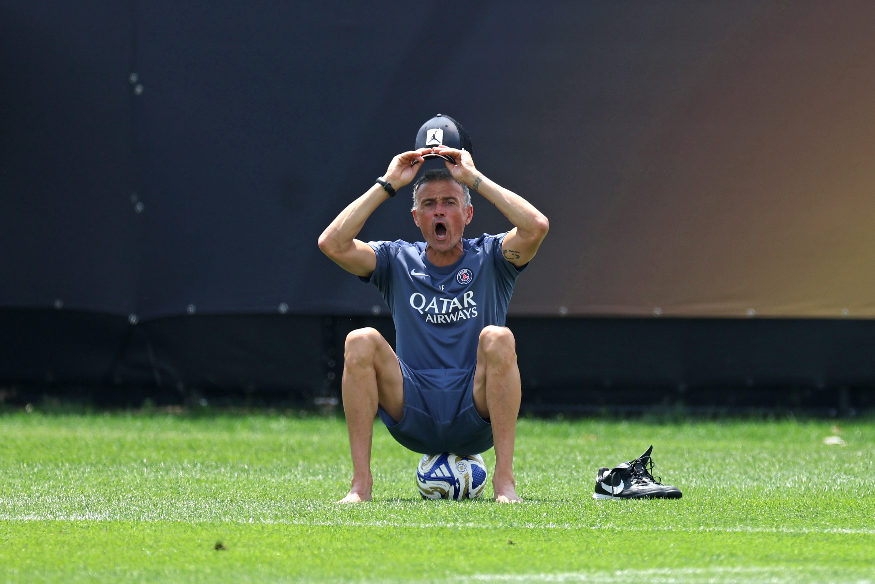 Luis Enrique, Head Coach of Paris Saint-Germain, reacts with his shoes off as he sits on an adidas FIFA Club World Cup match ball during a Paris Saint-Germain Training Session ahead of their FIFA Club World Cup 2025 Final match against Chelsea