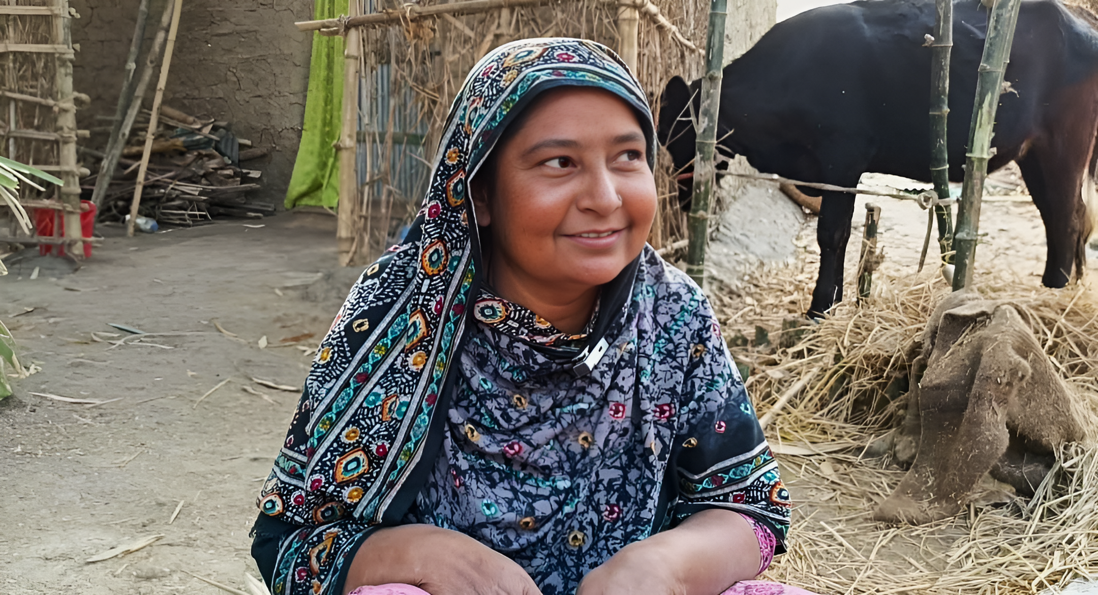 Josna Begum sitting outside her small cow shelter