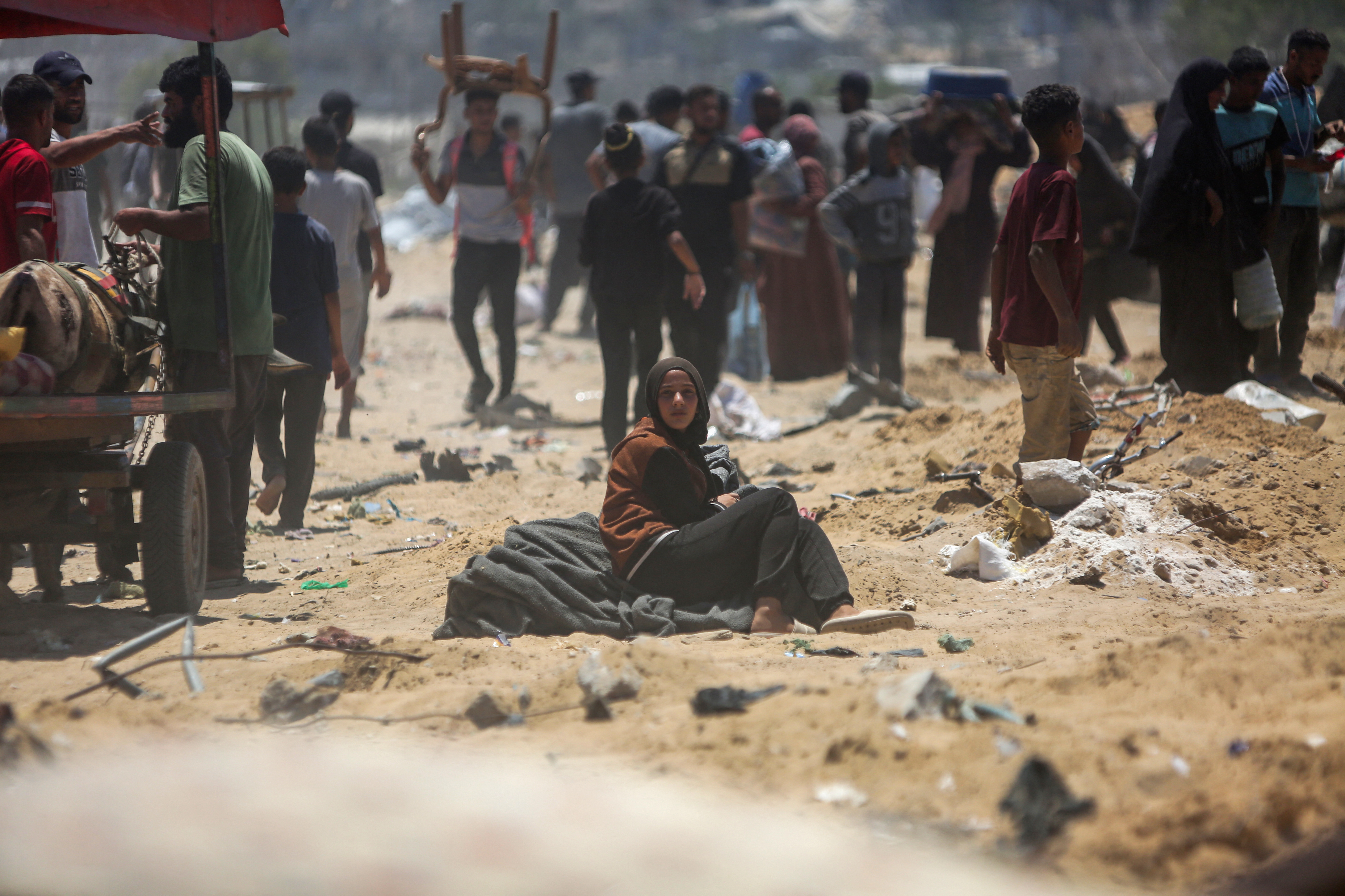A woman sitting on salvaged belongings looks on as Palestinians inspect destroyed tents at a makeshift displacement camp following a reported incursion a day earlier by Israeli tanks in the area in Khan Yunis in the southern Gaza strip on July 11, 2025. (Photo by AFP)