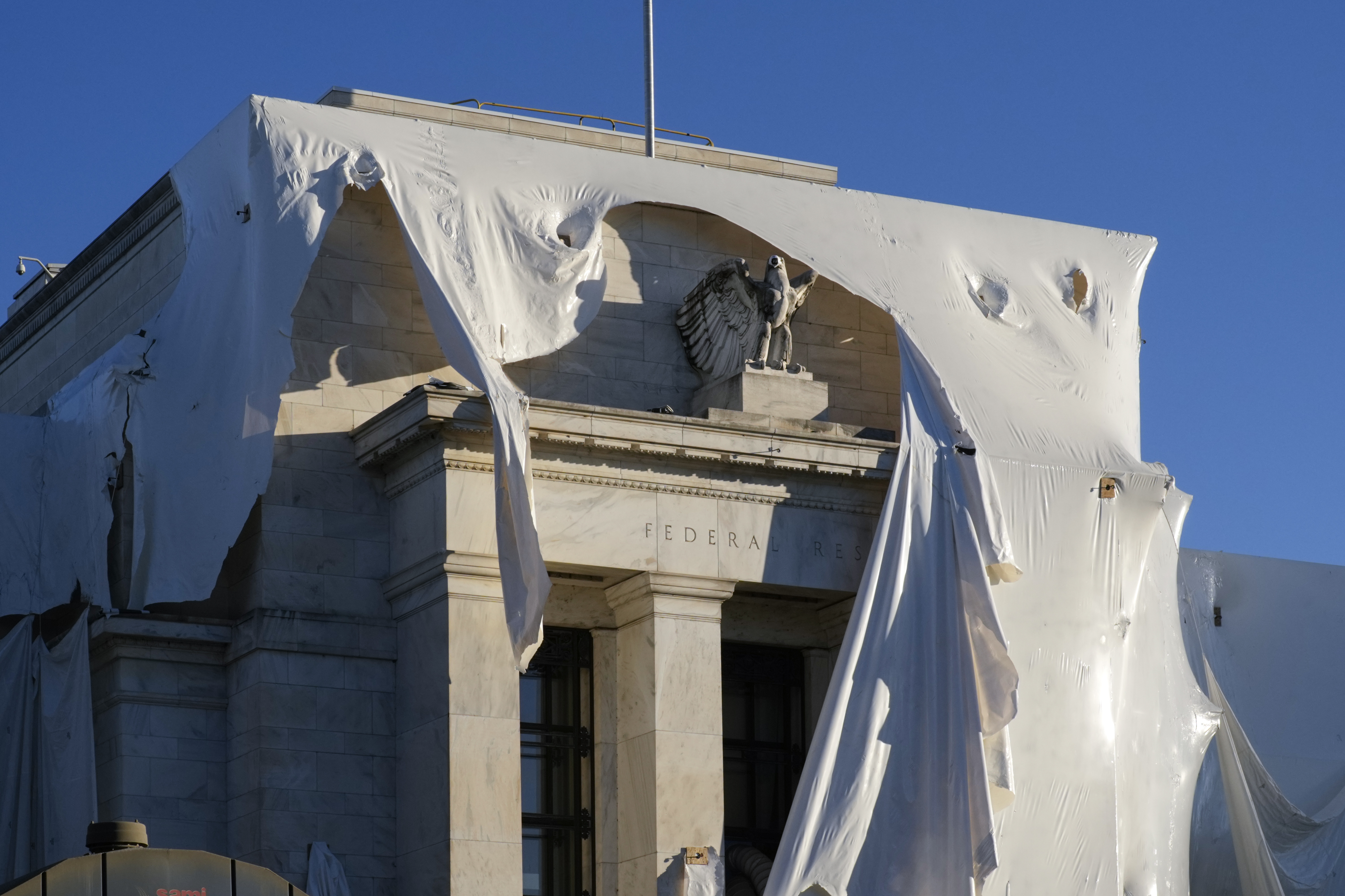 The sculpture of an eagle looks out from behind protective construction wrapping on the facade as the Federal Reserve Board Building undergoes both interior and exterior renovations, in Washington, Monday, Oct. 23, 2023. Last Thursday, Federal Reserve Chair Jerome Powell that inflation remains too high and that bringing it down to the Fed's target level will likely require a slower-growing economy and job market. (AP Photo/J. Scott Applewhite)