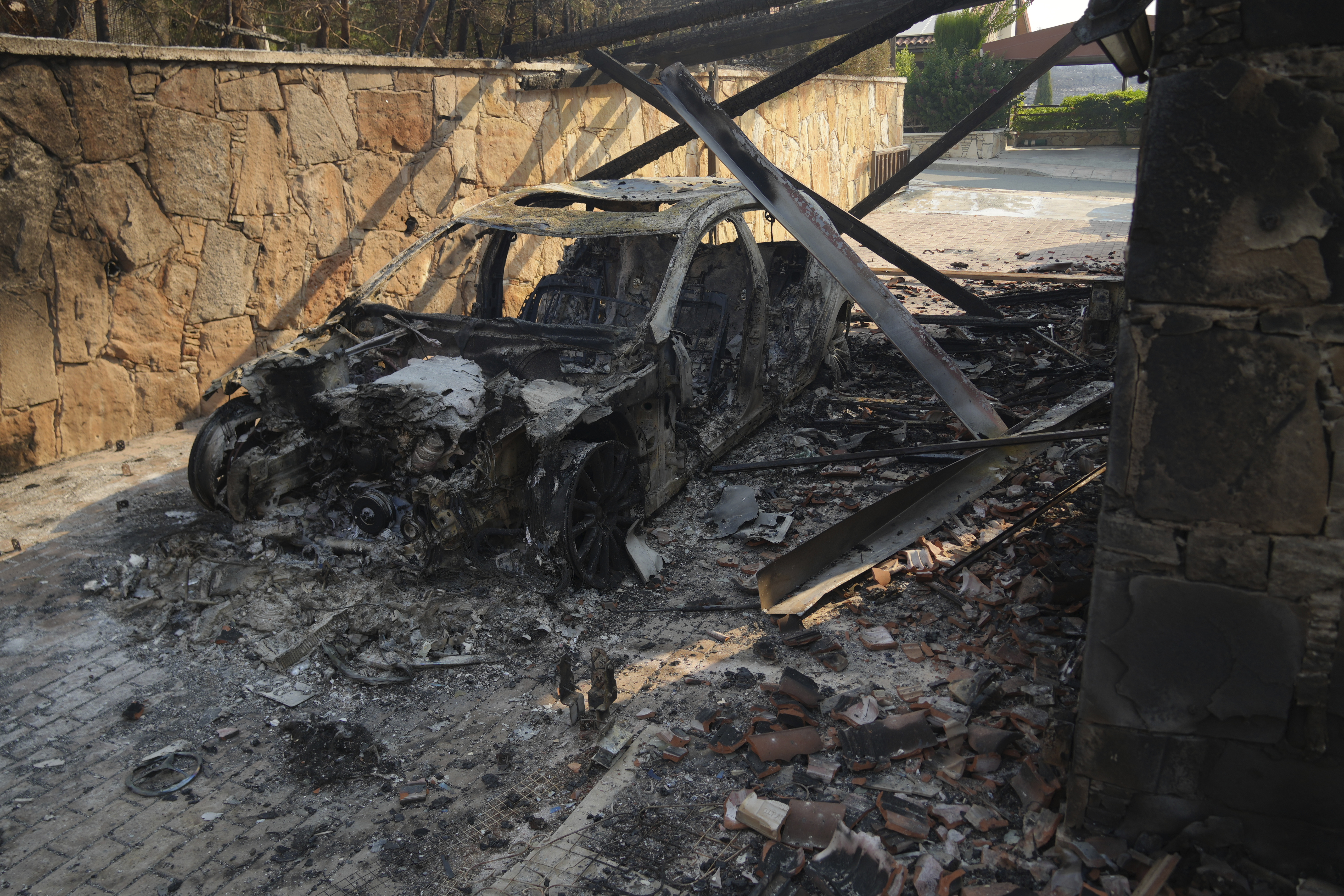 A burned car is seen in Souni village, Cyprus, during a massive wildfire on the southern side of the east Mediterranean island nation's Troodos mountain range, Thursday, July 24, 2025. (AP Photo/Petros Karadjias)