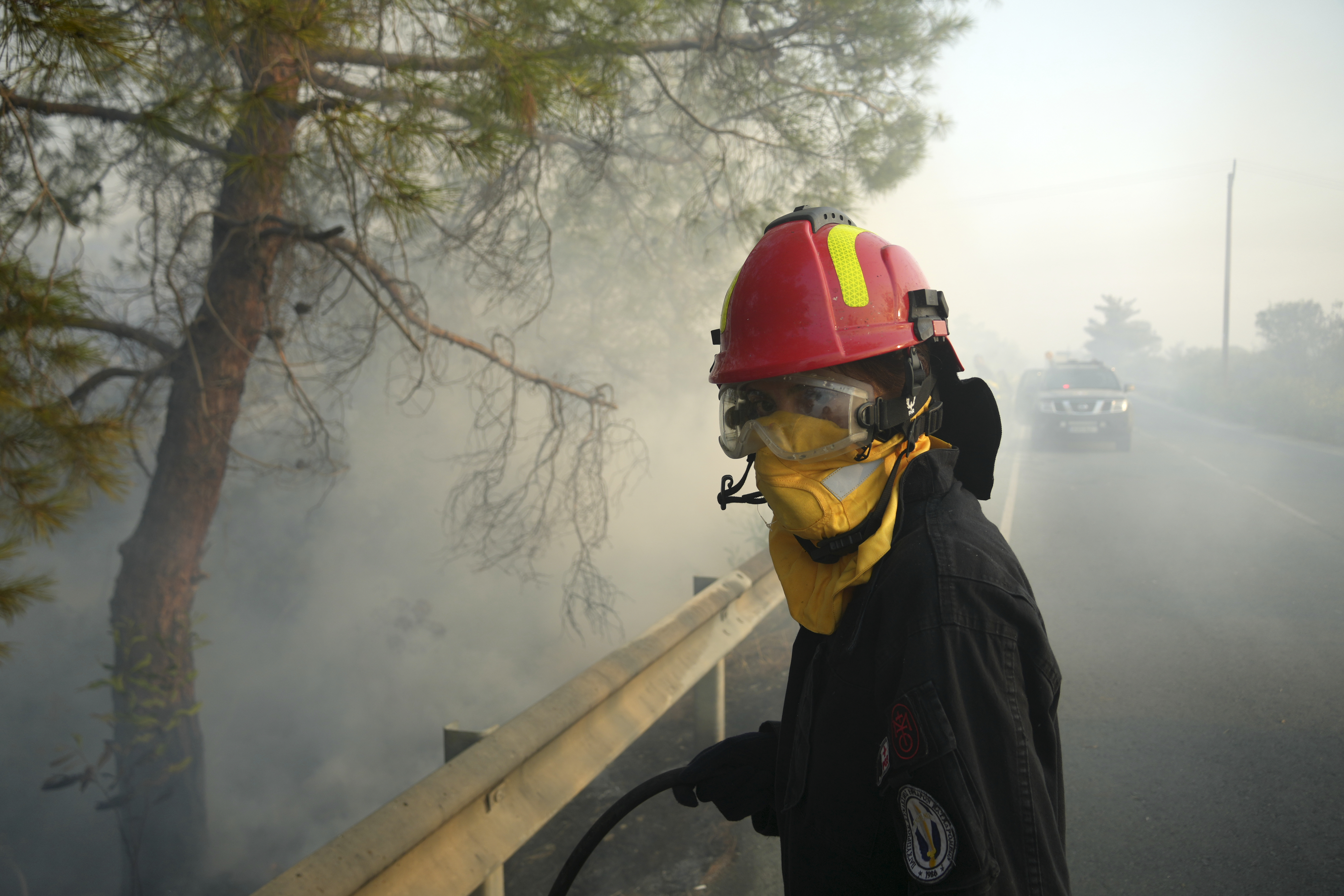 A firefighter along with her colleagues try to extinguish a fire in Souni village, Cyprus, during a massive wildfire on the southern side of the east Mediterranean island nation's Troodos mountain range, Thursday, July 24, 2025. (AP Photo/Petros Karadjias)