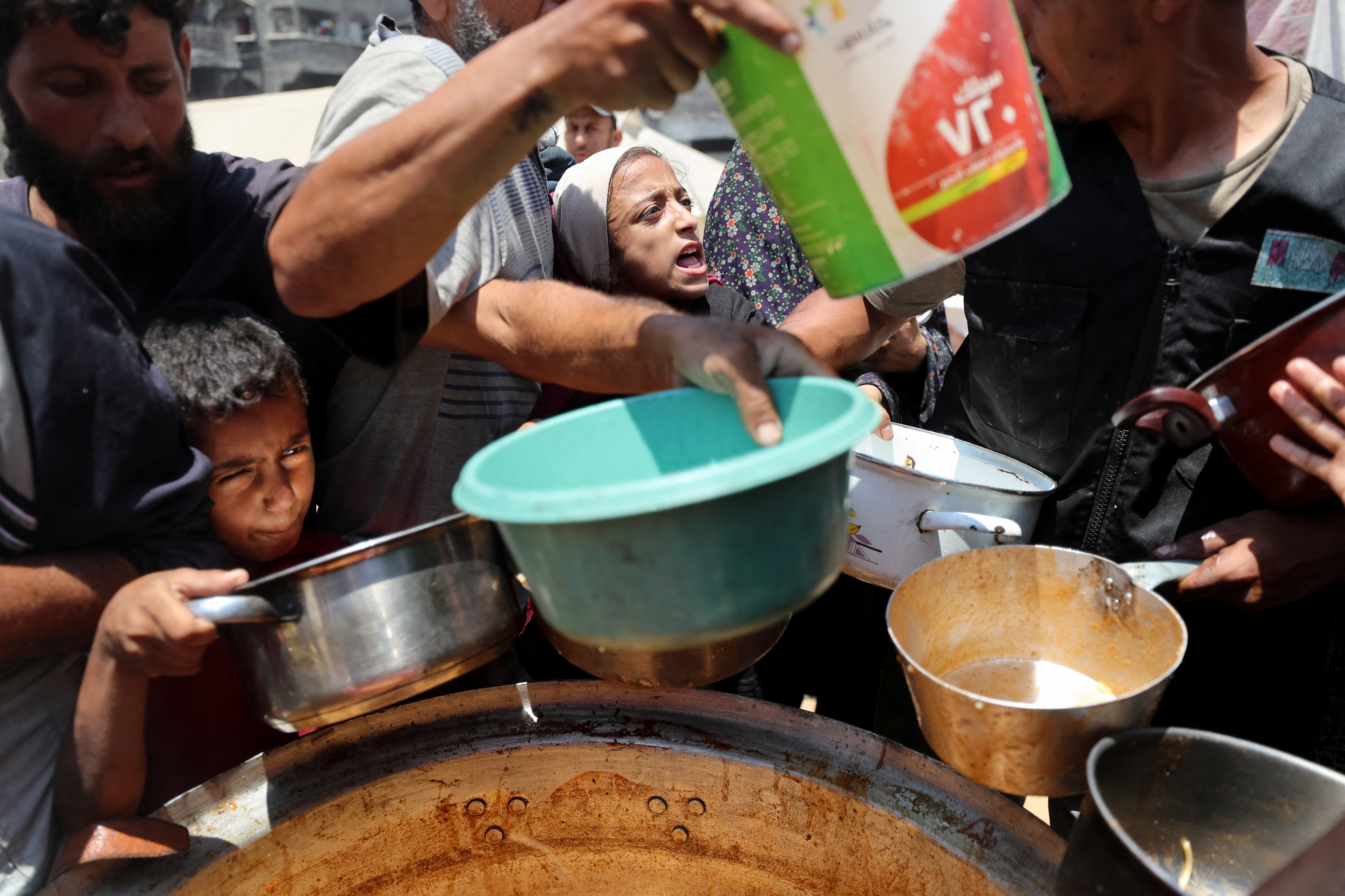 Palestinians wait to receive food cooked by a charity kitchen, in Gaza City in June 2025