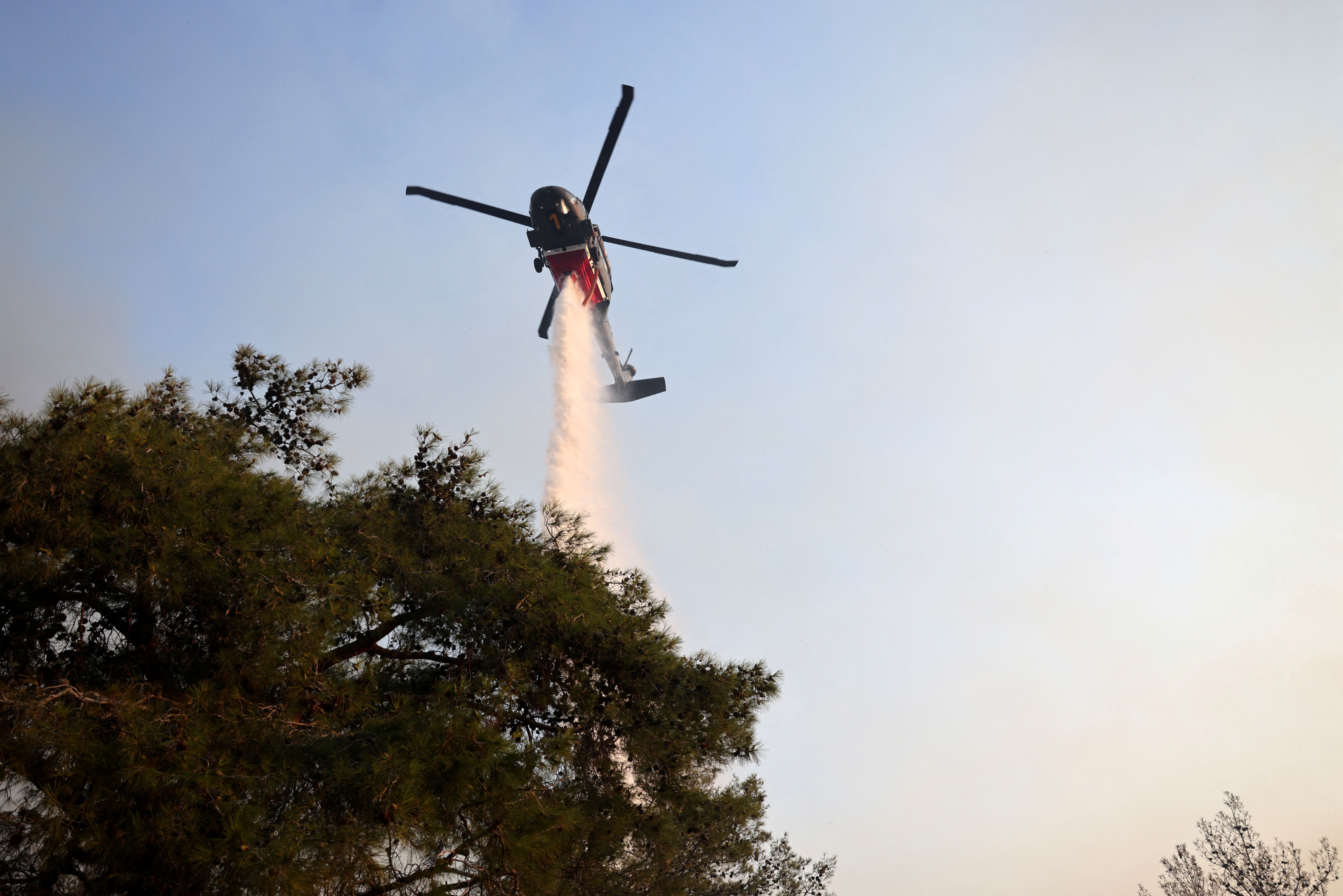 A firefighting helicopter drops water to extinguish fire at the area of Souni near Limassol, Cyprus July 24, 2025. REUTERS/Yiannis Kourtoglou