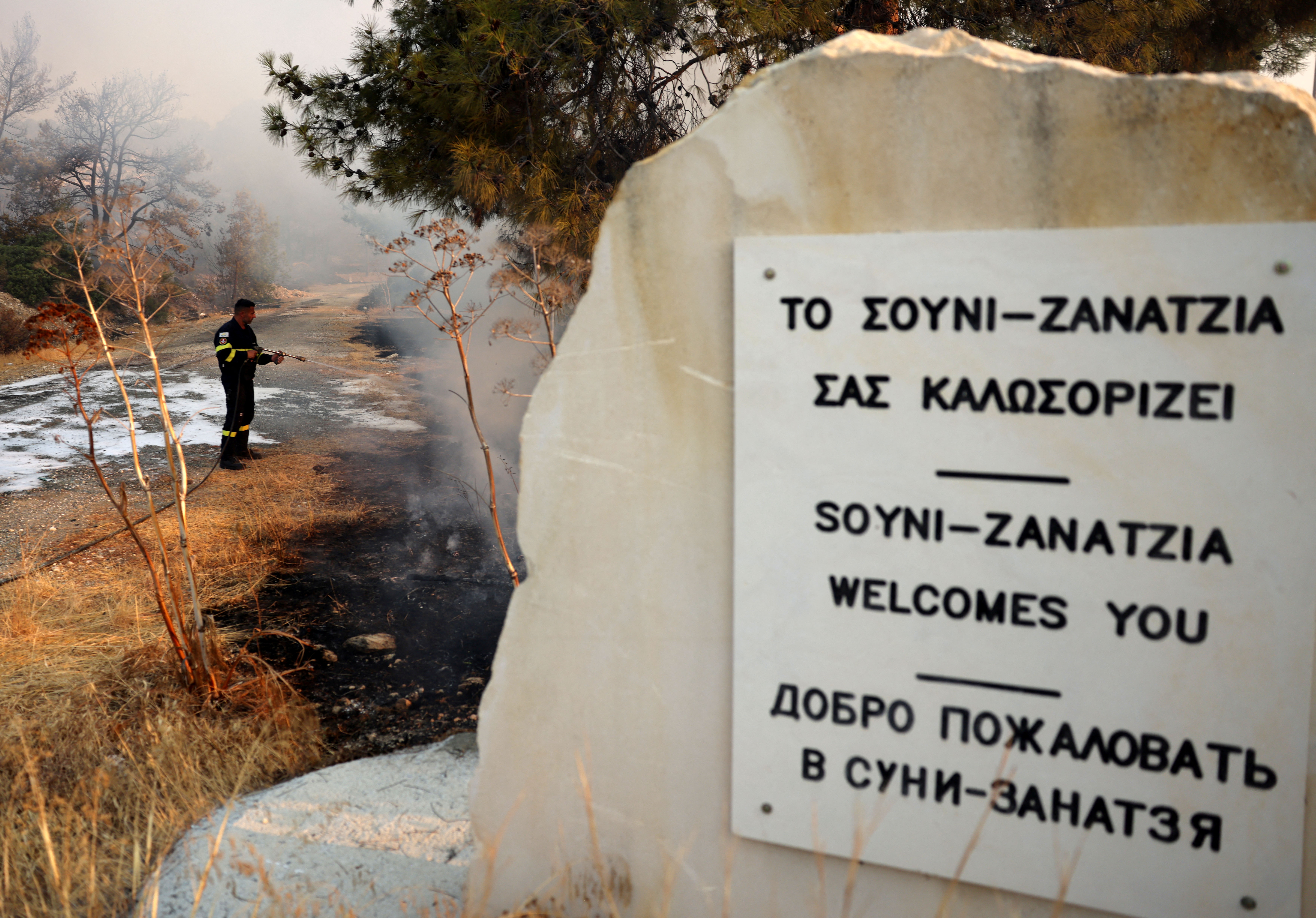 A firefighter uses a hose to cool a burnt area during a wildfire at the area of Souni, near Limassol, Cyprus July 24, 2025. REUTERS/Yiannis Kourtoglou